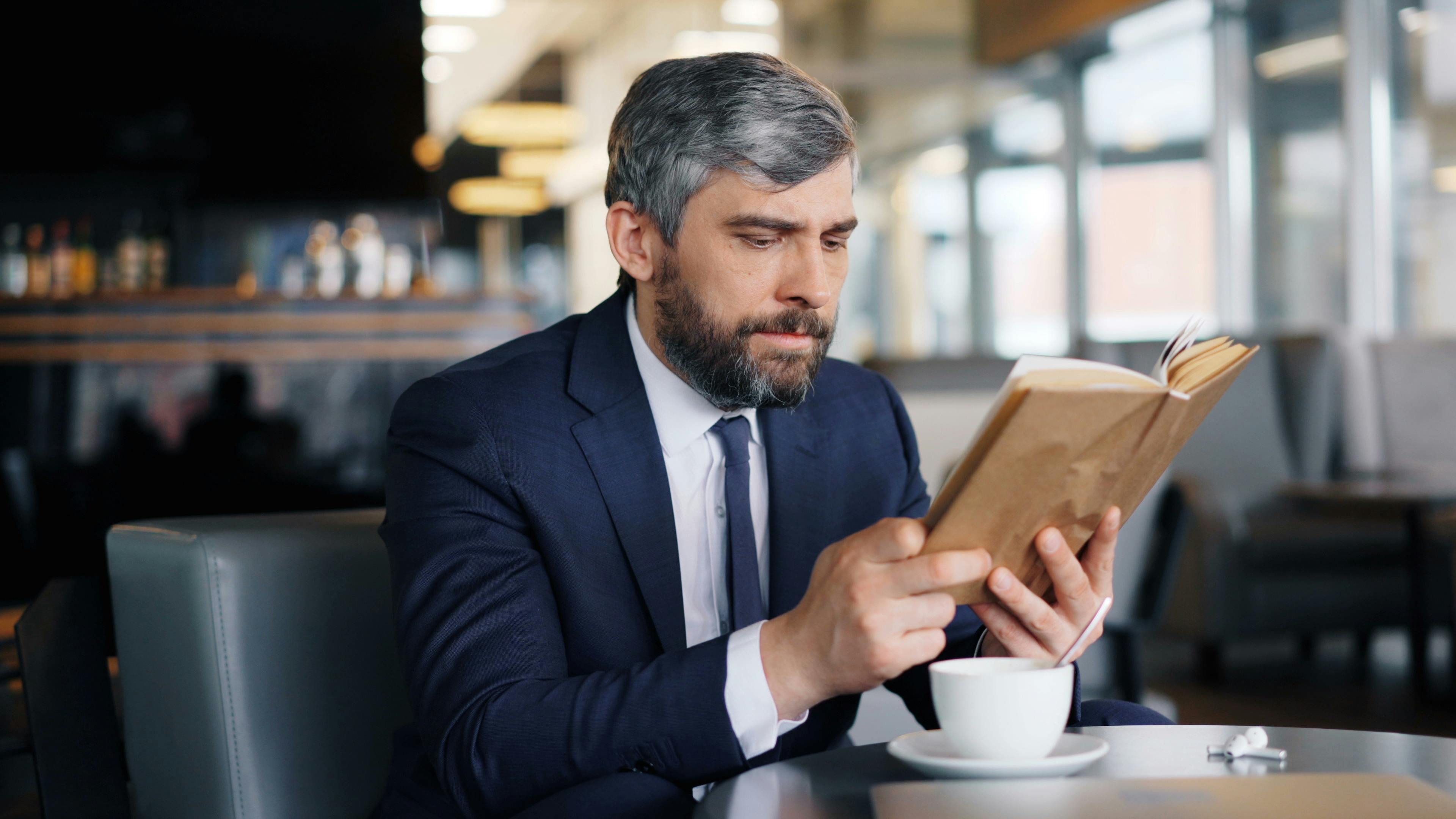 Un homme avec un livre dans un café | Source : Pexels