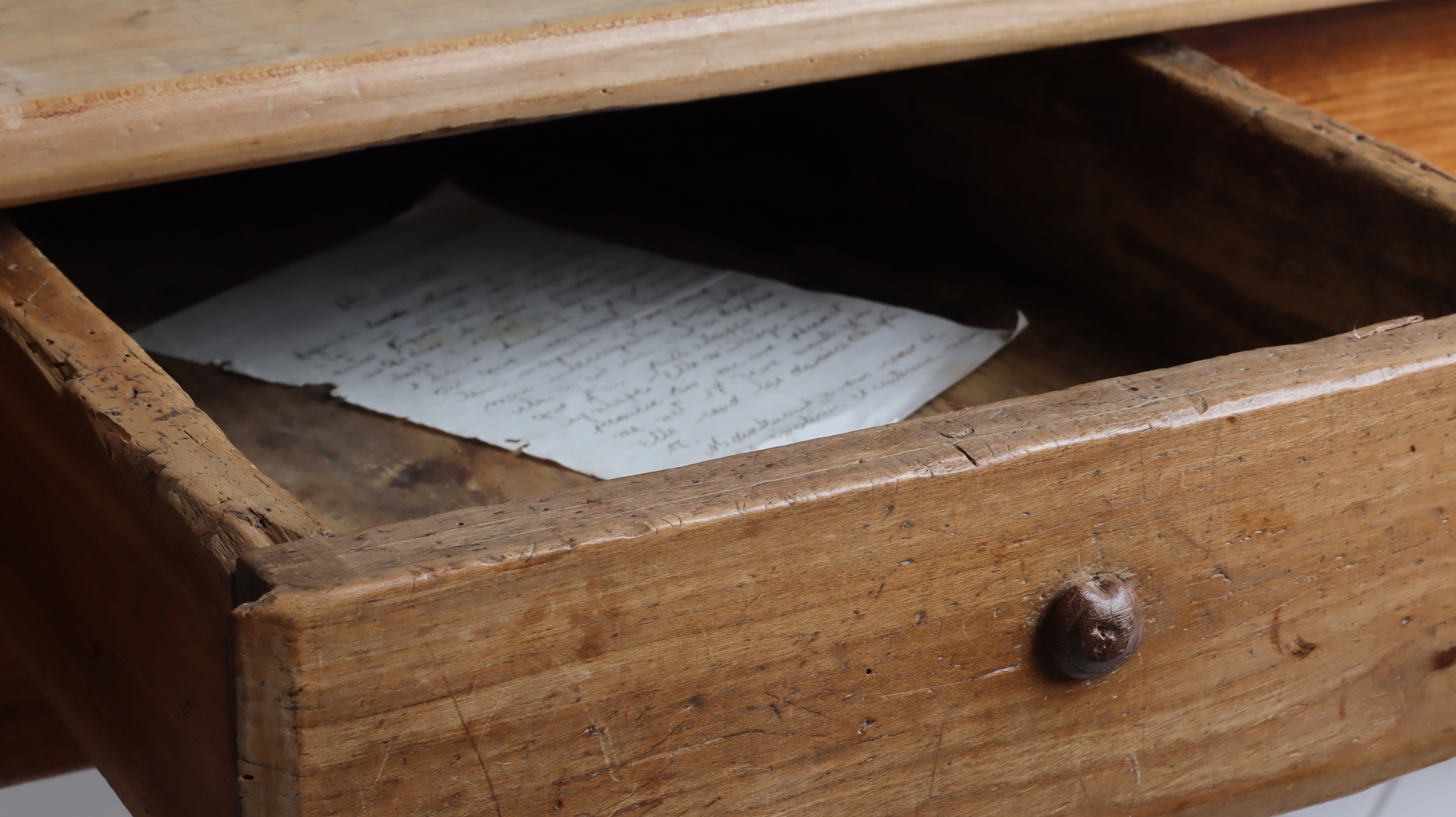 Tiroir entrouvert d'une vieille table en bois vintage avec une vieille lettre manuscrite à l'intérieur | Source : Shutterstock