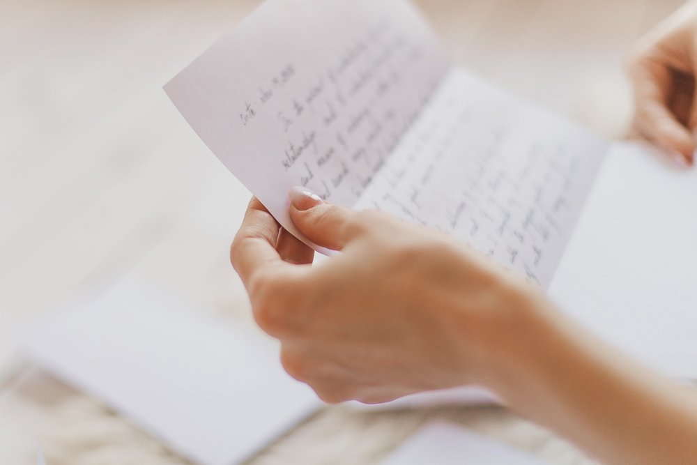 Les mains d'une jeune femme tenant une lettre manuscrite. | Shutterstock