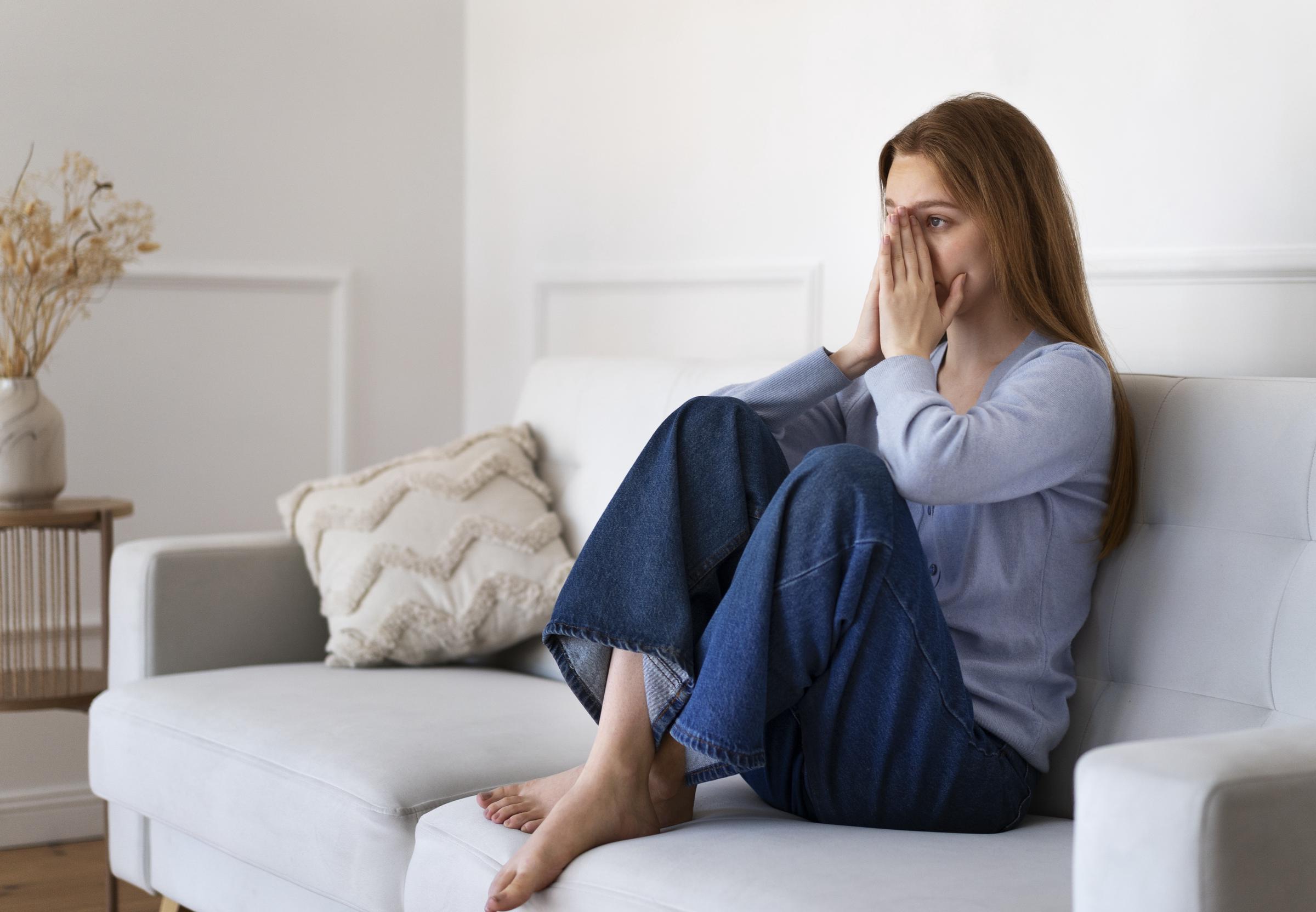 Une femme inquiète assise sur le canapé | Source : Freepik