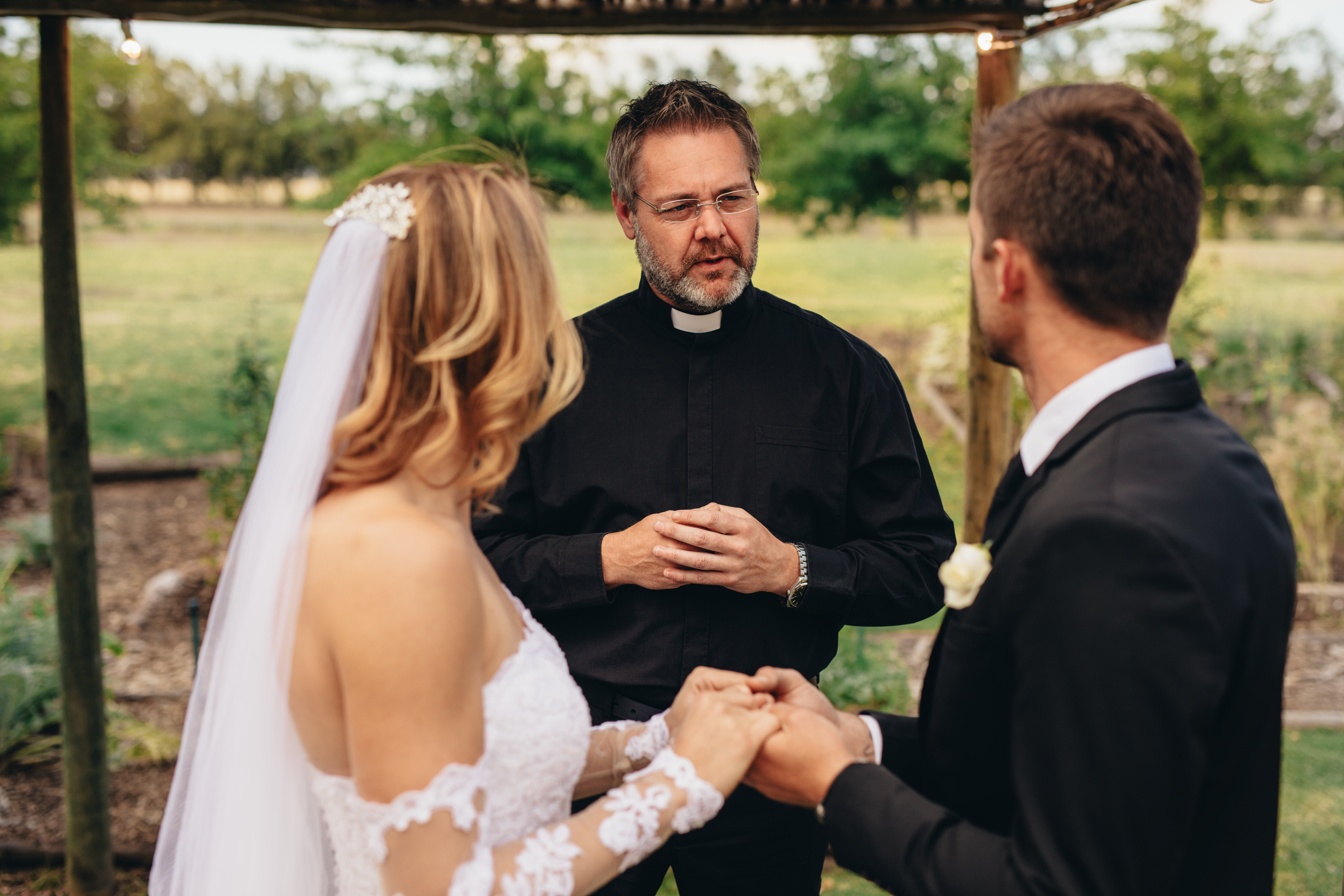 Un prêtre marie un couple lors d'une belle cérémonie de mariage en plein air. | Photo : Shutterstock