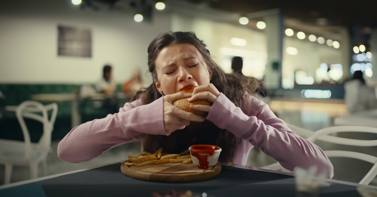 Chica come frenéticamente una hamburguesa | Fuente: YouTube/LoveBuster