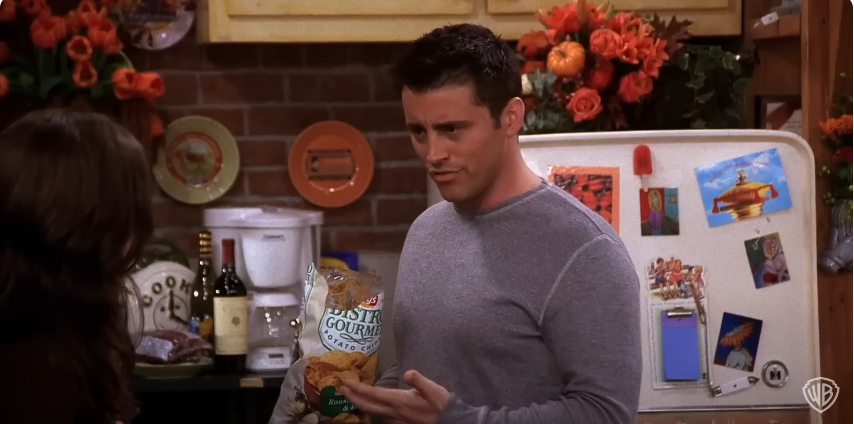 Matt Leblanc dans le rôle de Joey tenant un paquet de chips sur le plateau de "Friends". Source