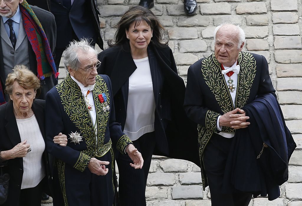 La journaliste française Anne Sinclair et son compagnon Pierre Nora arrivent pour assister à la cérémonie d'obsèques de l'écrivain et universitaire français Alain Decaux, le 4 avril 2016, à l'hôtel des Invalides. | Photo : Getty Images