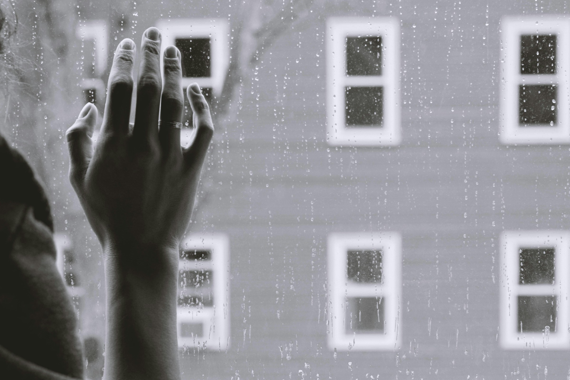 Photo en niveaux de gris de la main droite d'une femme sur un vitre | Source : Pexels