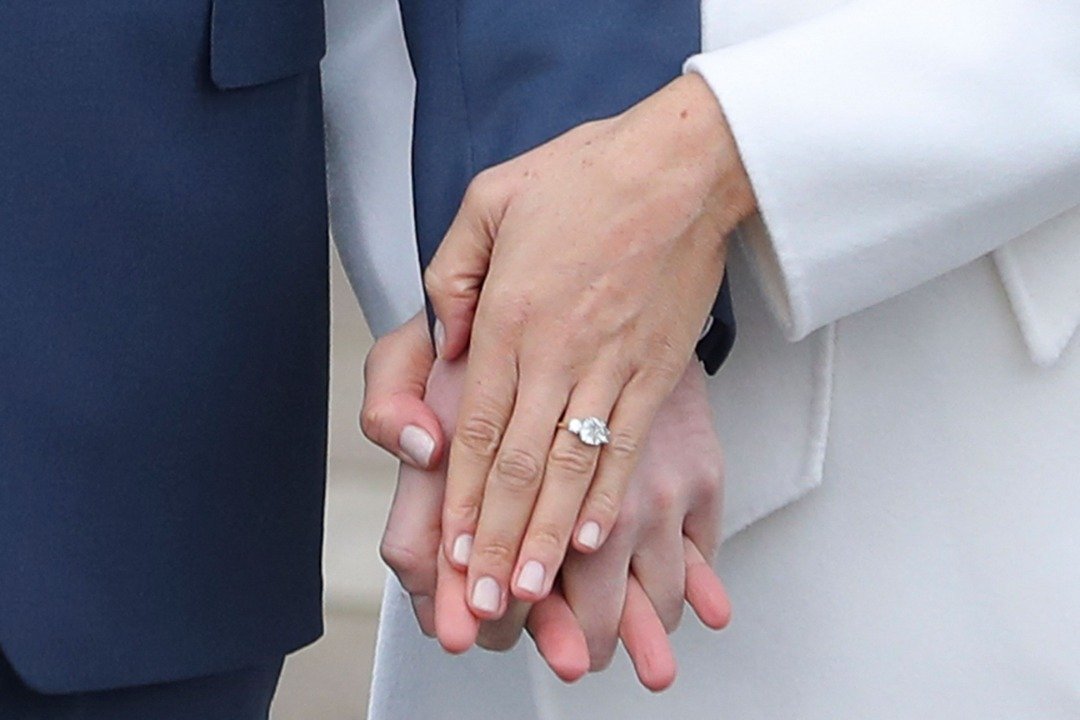 Le prince britannique Harry se tient aux côtés de sa fiancée, l'actrice américaine Meghan Markle, qui montre sa bague de fiançailles alors qu'ils posent pour une photo dans le Sunken Garden du palais de Kensington, dans l'ouest de Londres, le 27 novembre 2017, après l'annonce de leurs fiançailles | Source : Getty Images