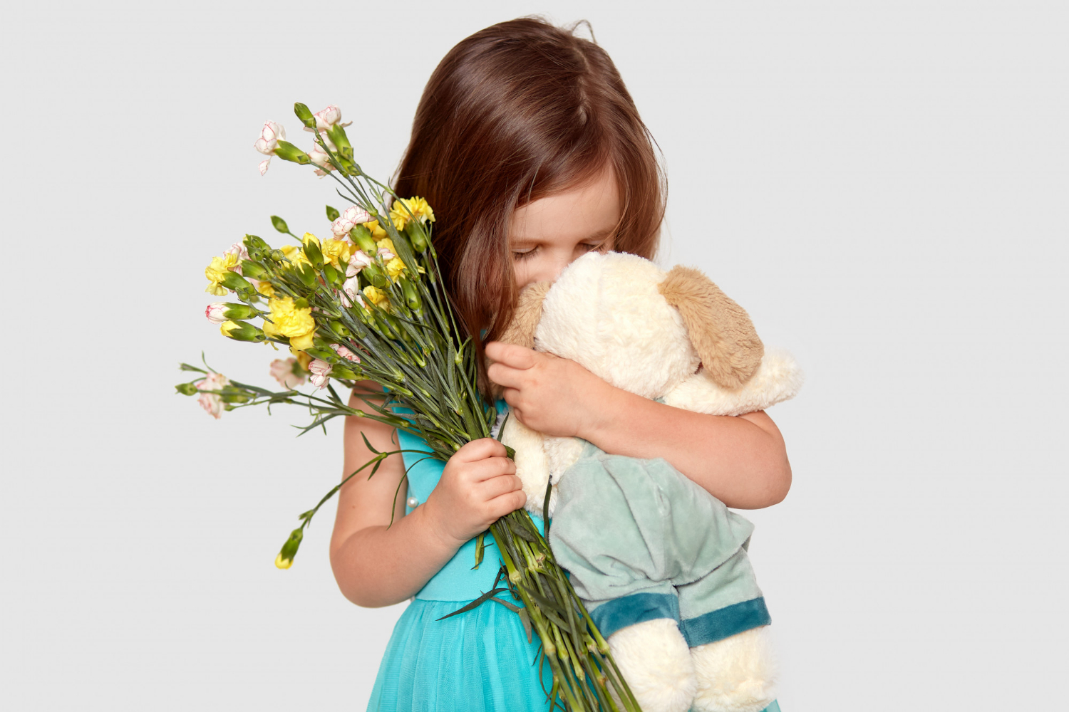 Une petite fille triste tenant sa peluche et des fleurs | Source : Freepik