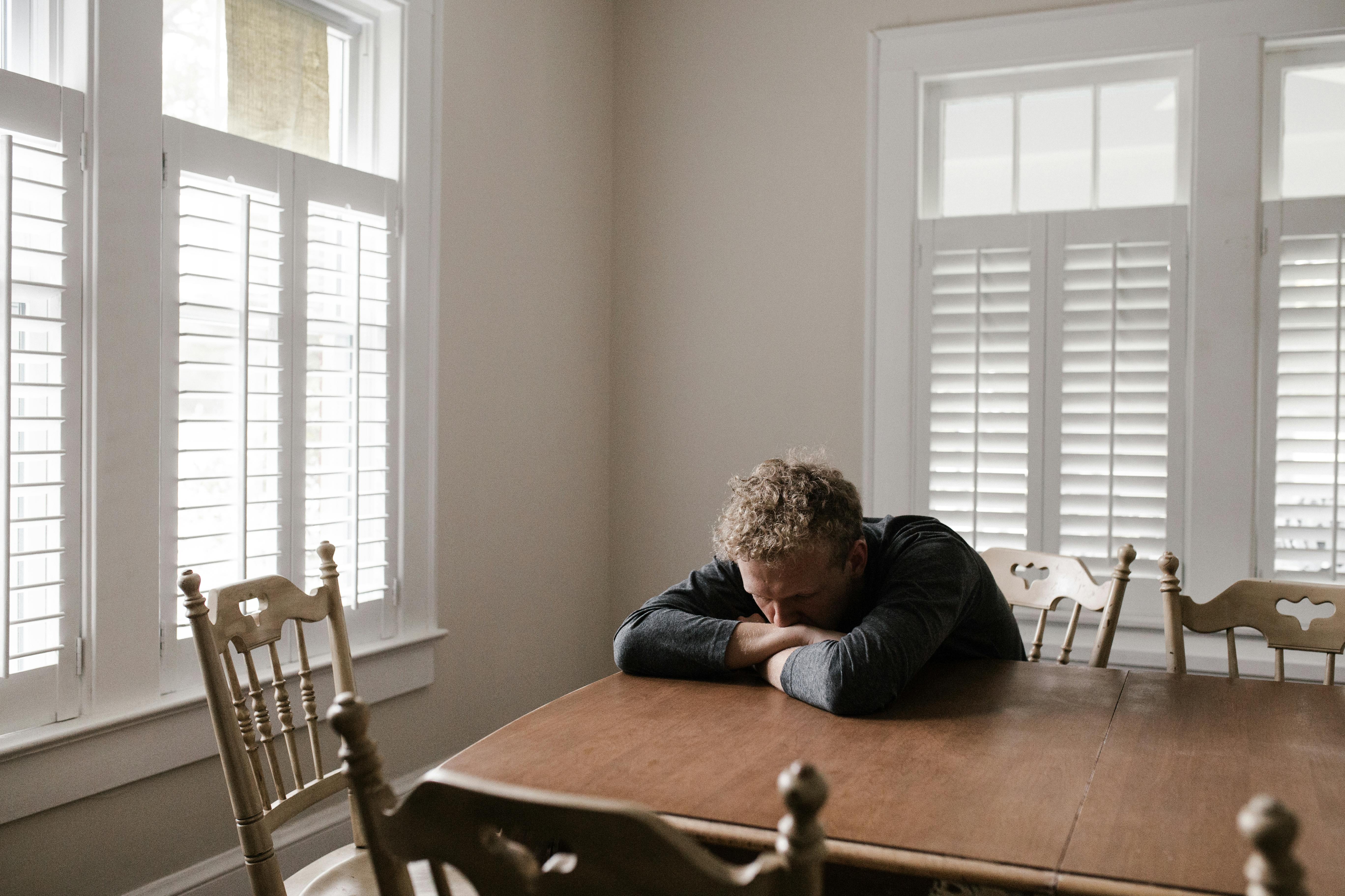 Un homme anxieux allongé sur ses bras à une table | Source : Pexels