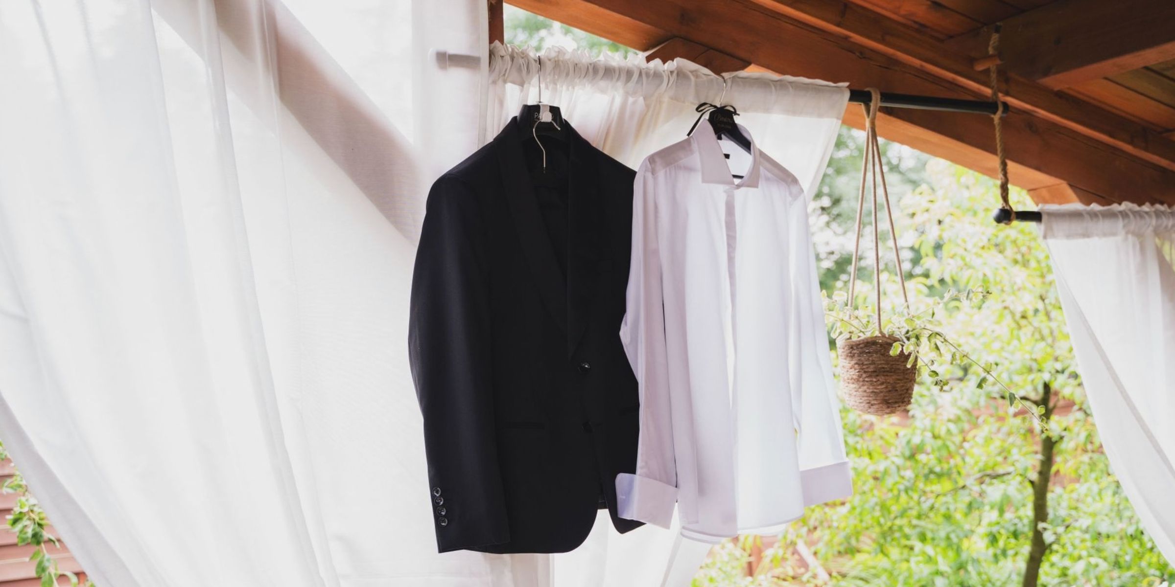 Un costume noir et une chemise blanche sont suspendus à un support en bois à l'extérieur | Source : Pexels