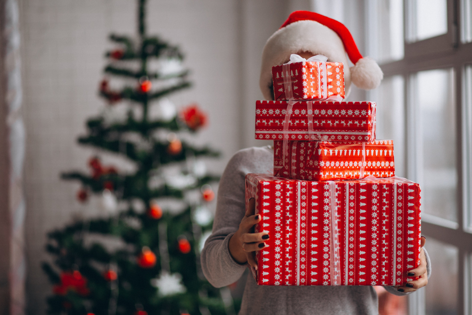 Une femme tenant une pile de cadeaux de Noël | Source : Freepik
