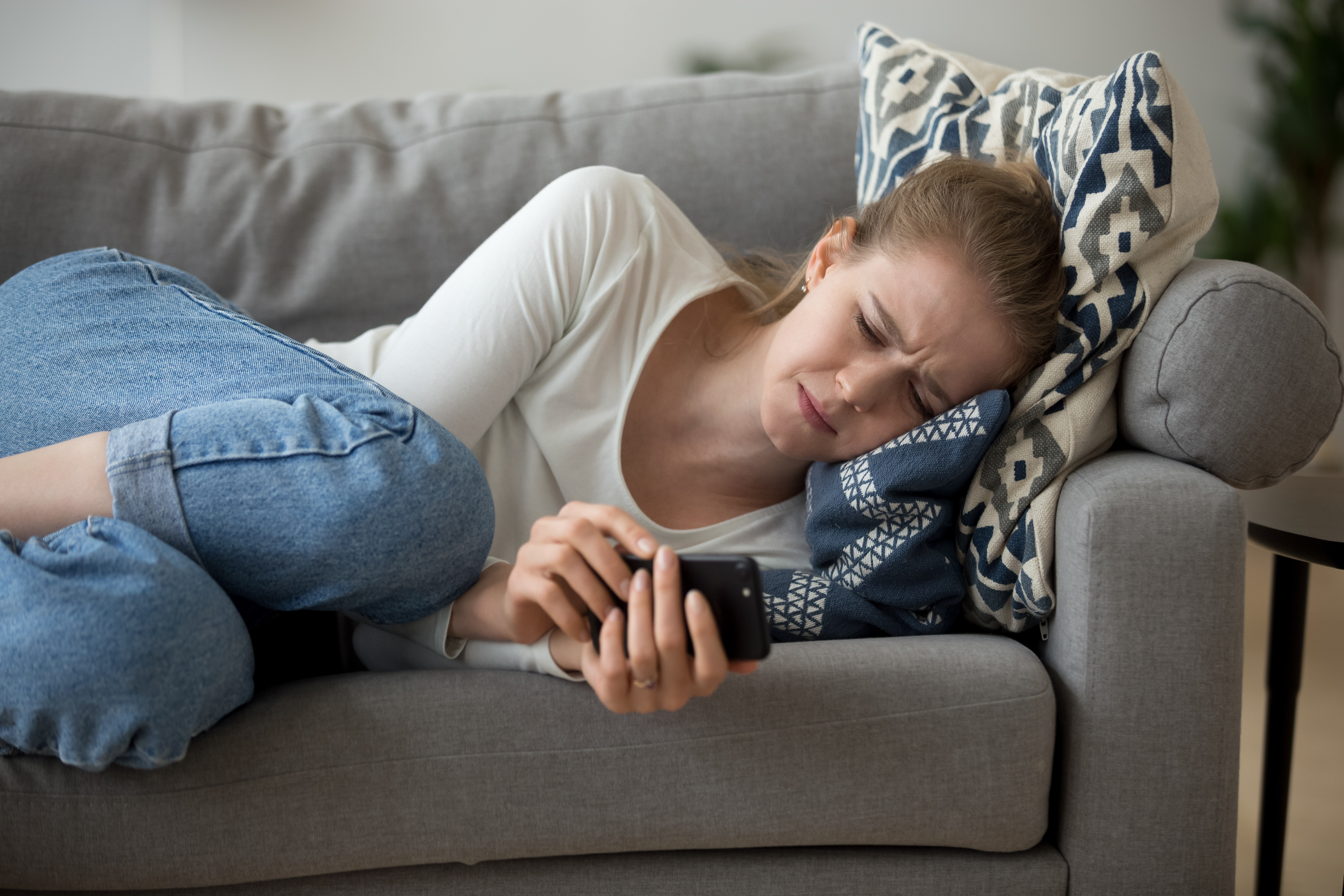 Une jeune femme pleure en regardant son téléphone | Source : Shutterstock