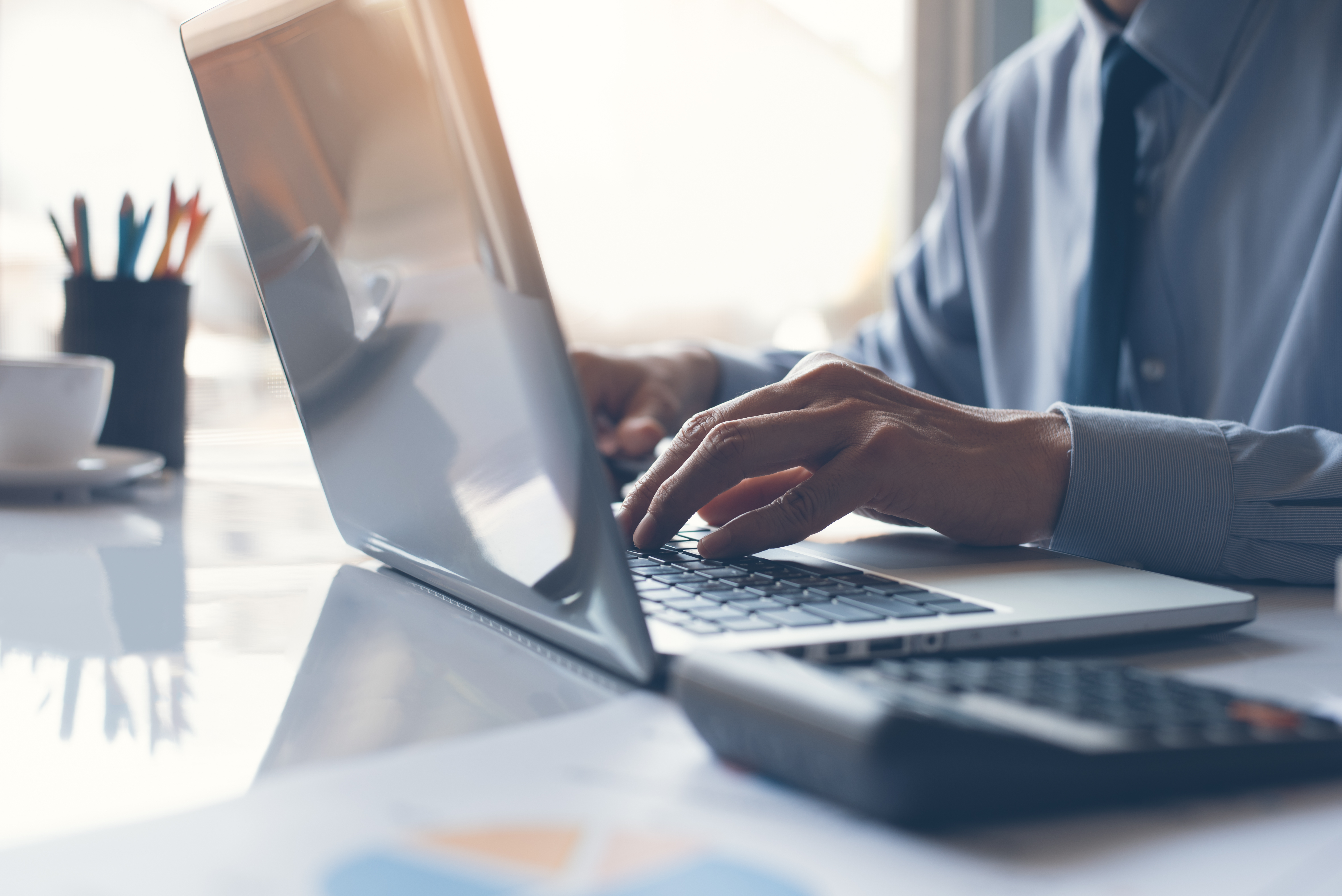 Homme d'affaires ou comptable travaillant sur un ordinateur portable avec un document d'affaires. | Source : Shutterstock