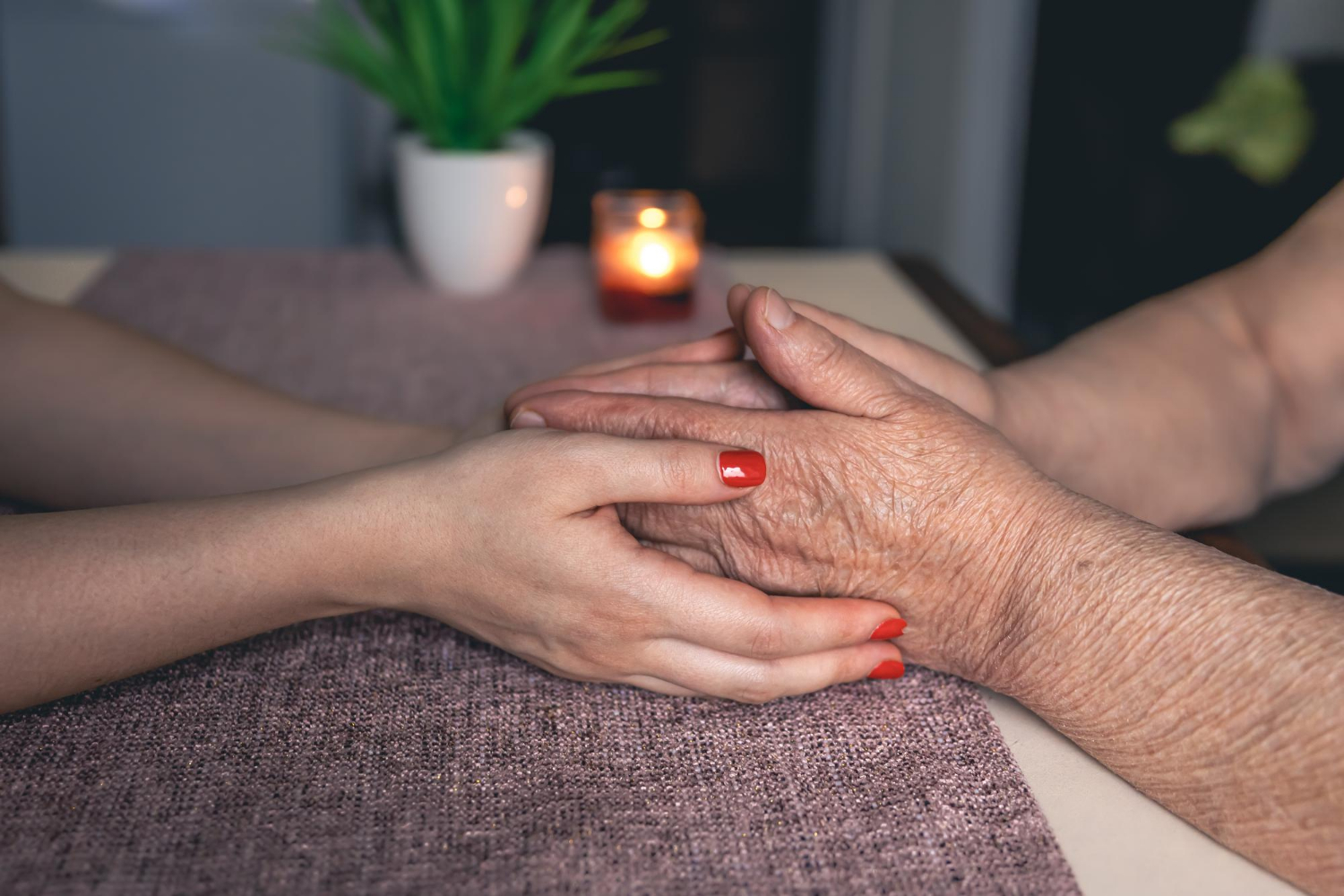 Une jeune femme tenant les mains d'une dame plus âgée de manière rassurante | Source : Freepik