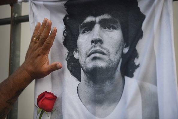 Un fan met sa main avec une rose sur un T-shirt avec la photo de la star du football Diego Maradona le jour de sa mort.  |Photo : Getty Images