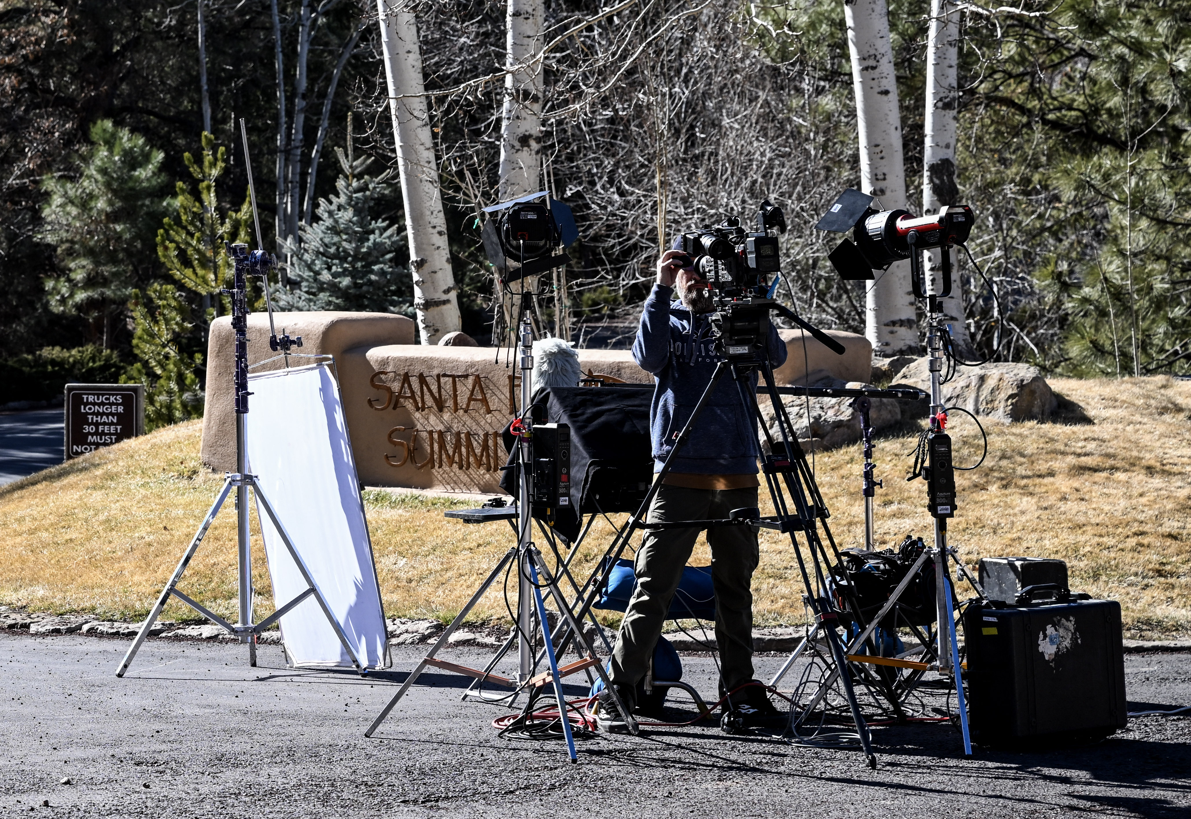 Un journaliste installe une caméra à l'entrée du quartier de Santa Fe Summit où vivait feu l'acteur Gene Hackman, le 28 février 2025 | Source : Getty Images