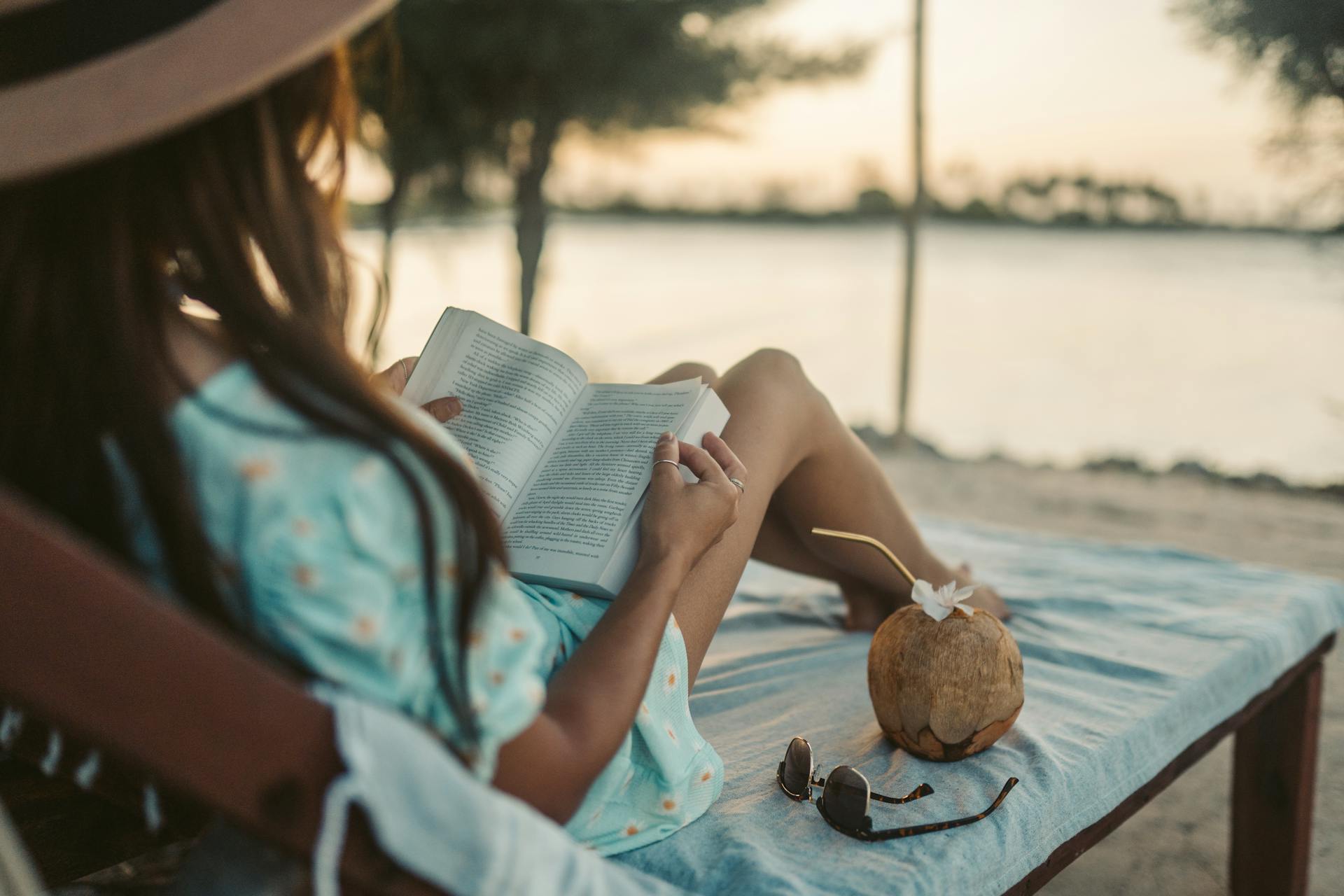 Une femme allongée sur une chaise longue et lisant un livre | Source : Pexels