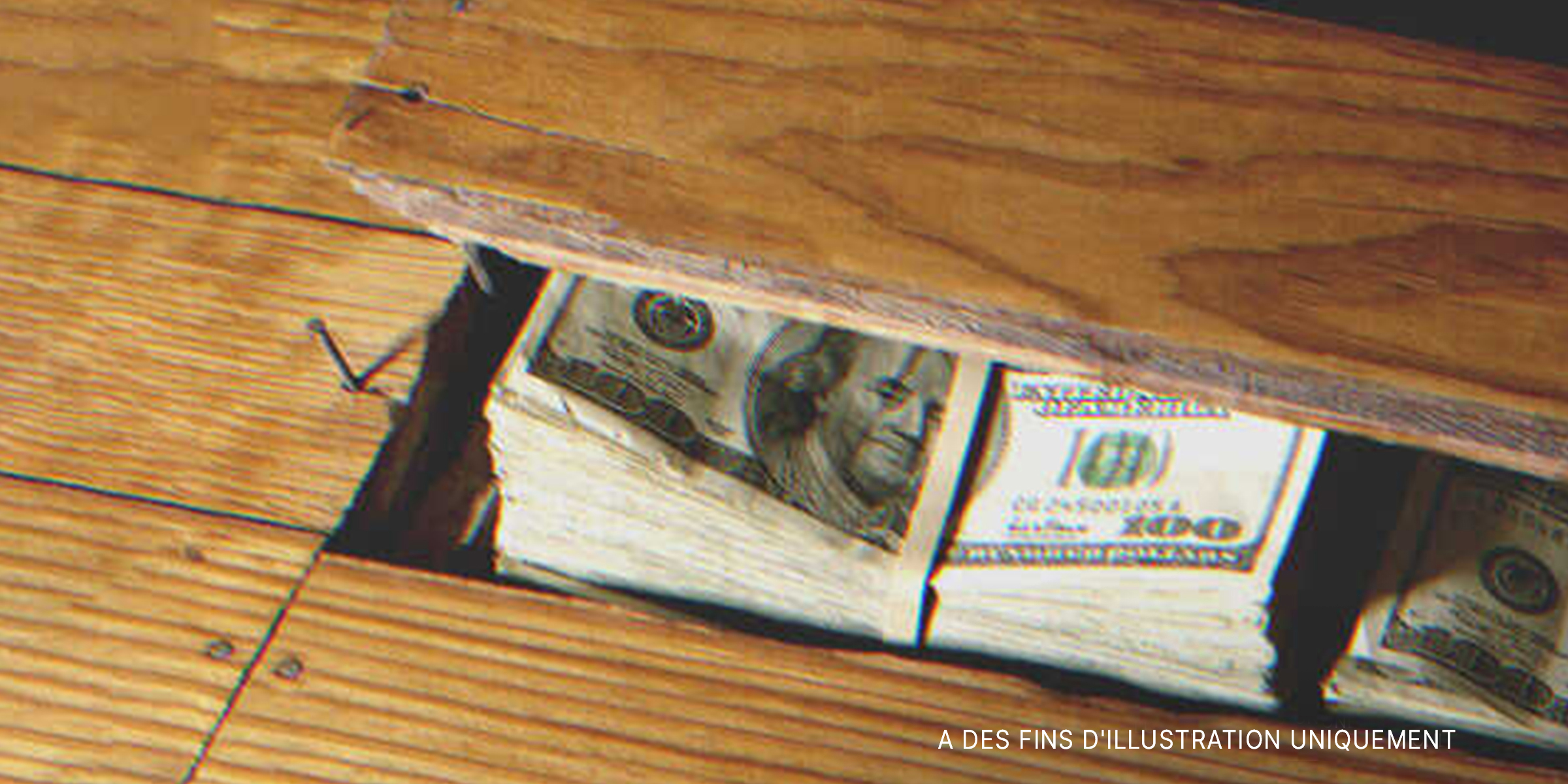 Des liasses de billets sous un parquet en bois. | Source : Getty Images
