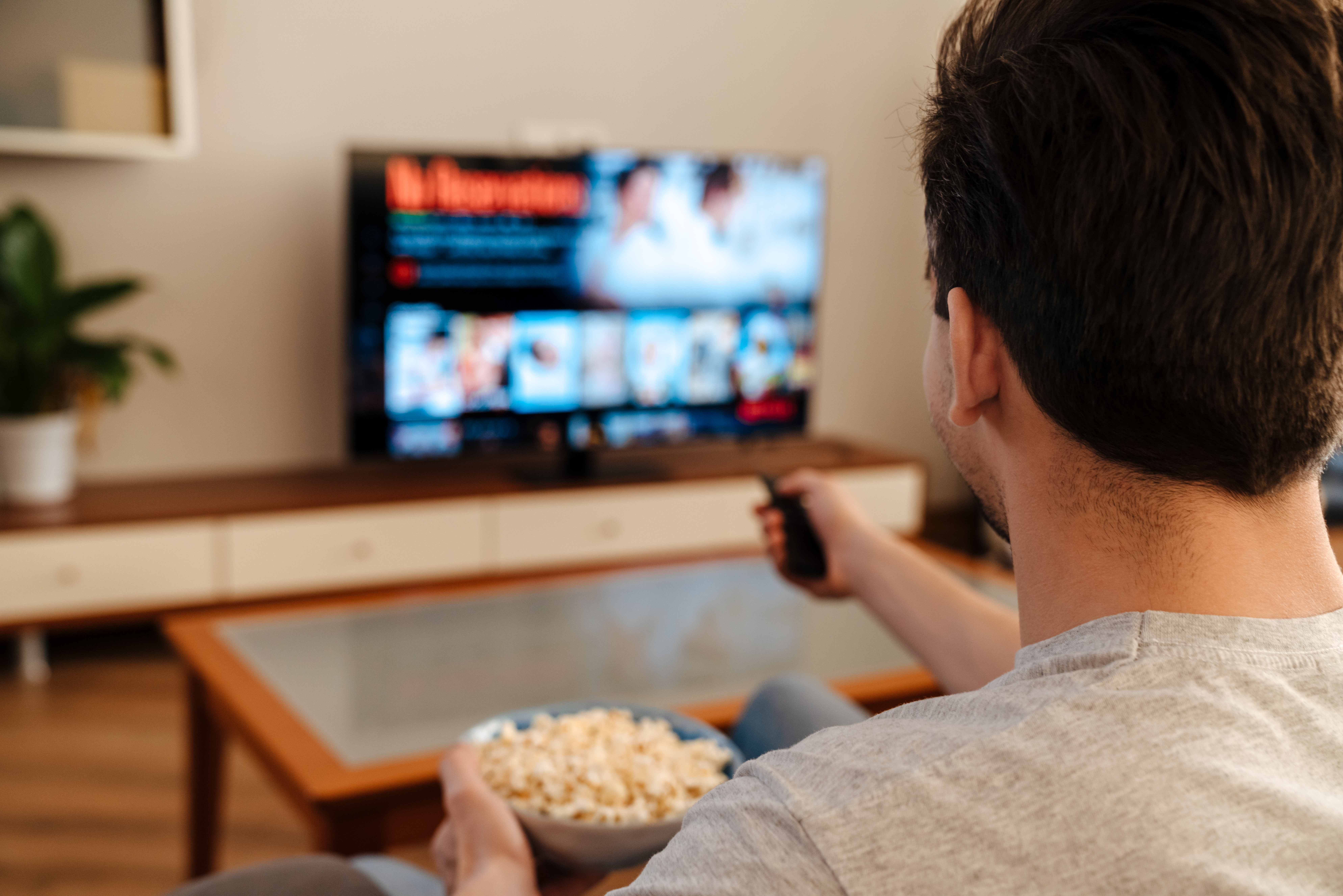 Un homme regardant la télévision et mangeant du pop-corn à la maison | Source : Shutterstock