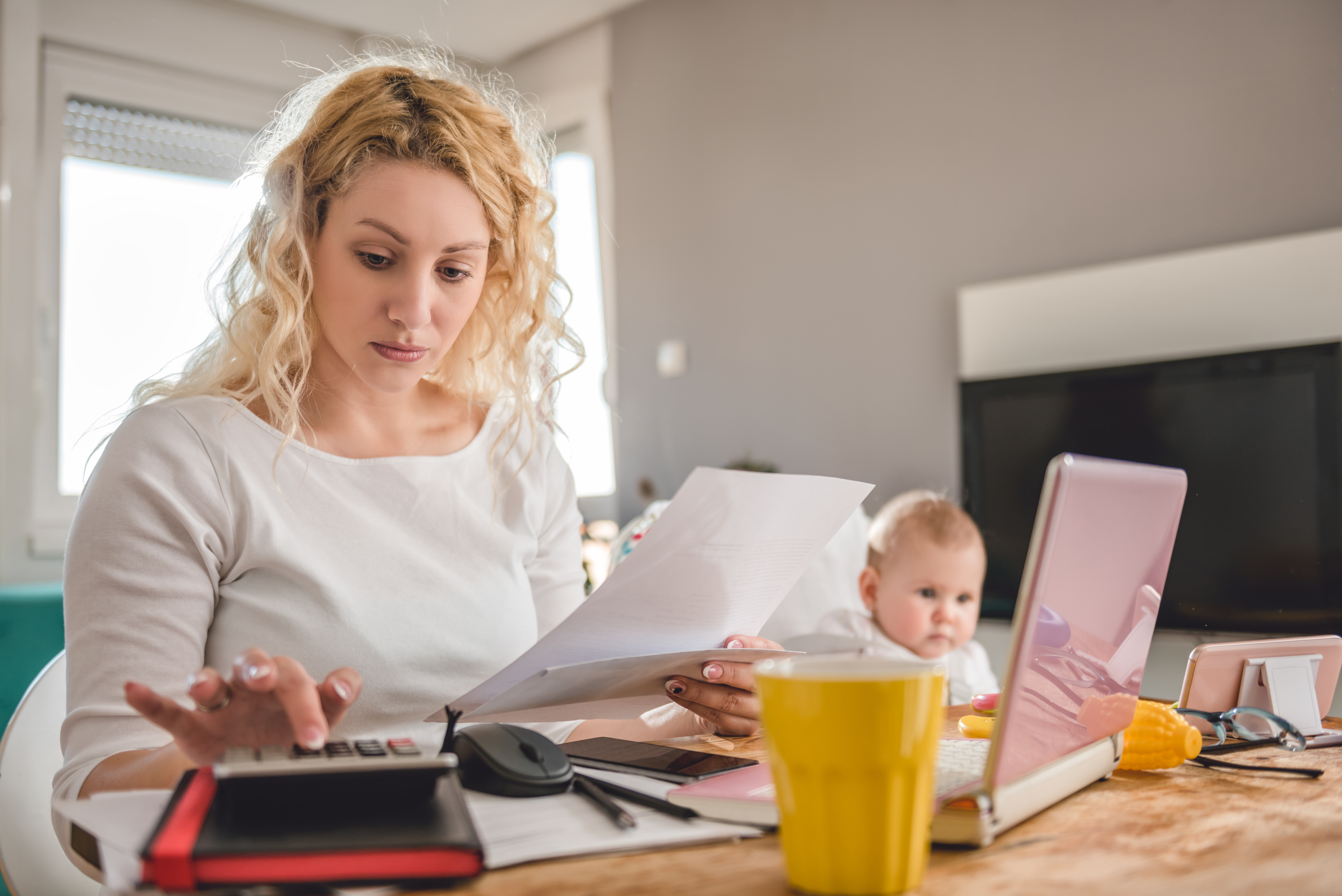 Une femme avec un enfant tenant une feuille de papier tout en calculant | Source : Shutterstock