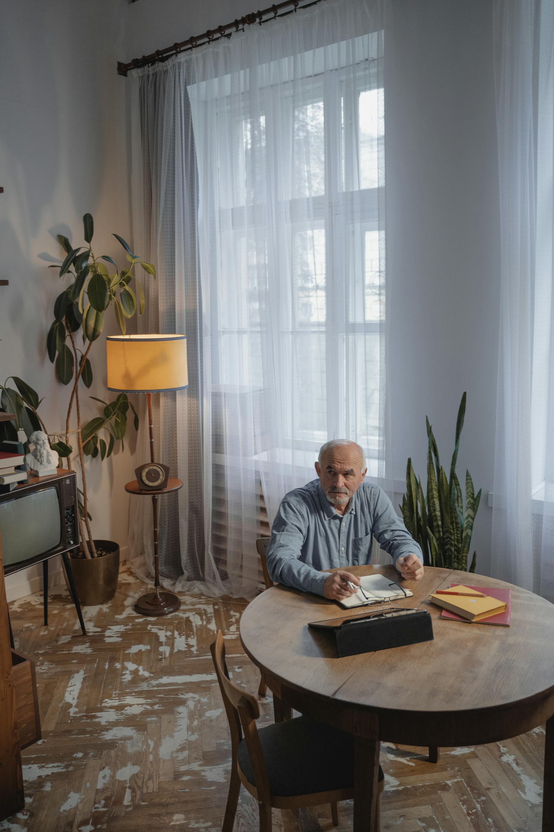 Un homme âgé assis sur une chaise en bois marron qui regarde vers le haut | Source : Pexels