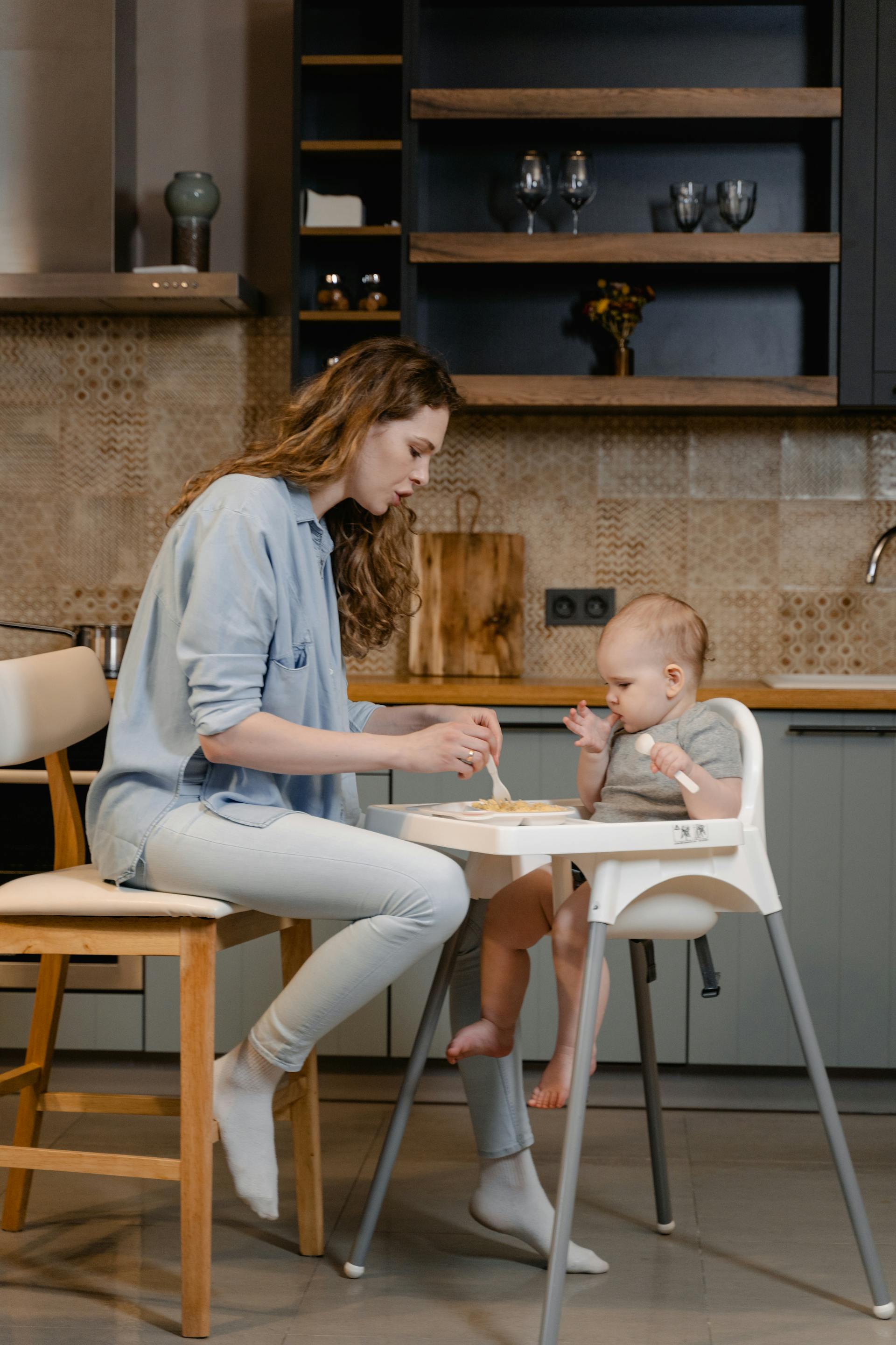 Une femme assise sur une chaise tout en nourrissant son bébé | Source : Pexels