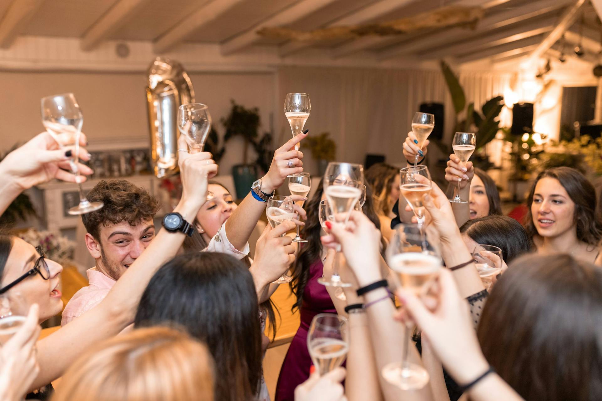 Jeunes hommes et jeunes femmes levant leurs verres de boisson dans un restaurant | Source : Pexels