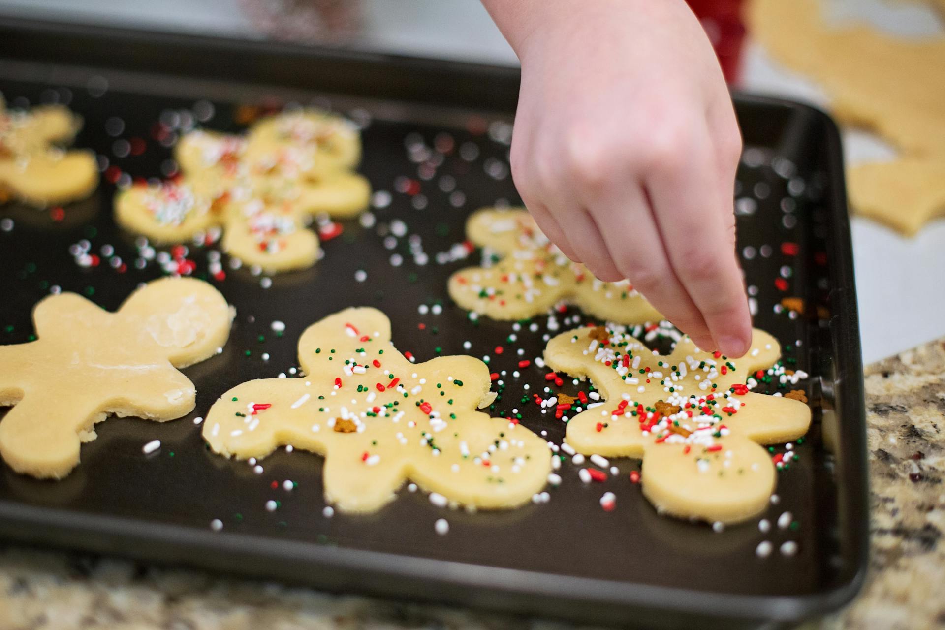 Une fille versant des paillettes sur des biscuits en pain d'épices | Source : Pexels