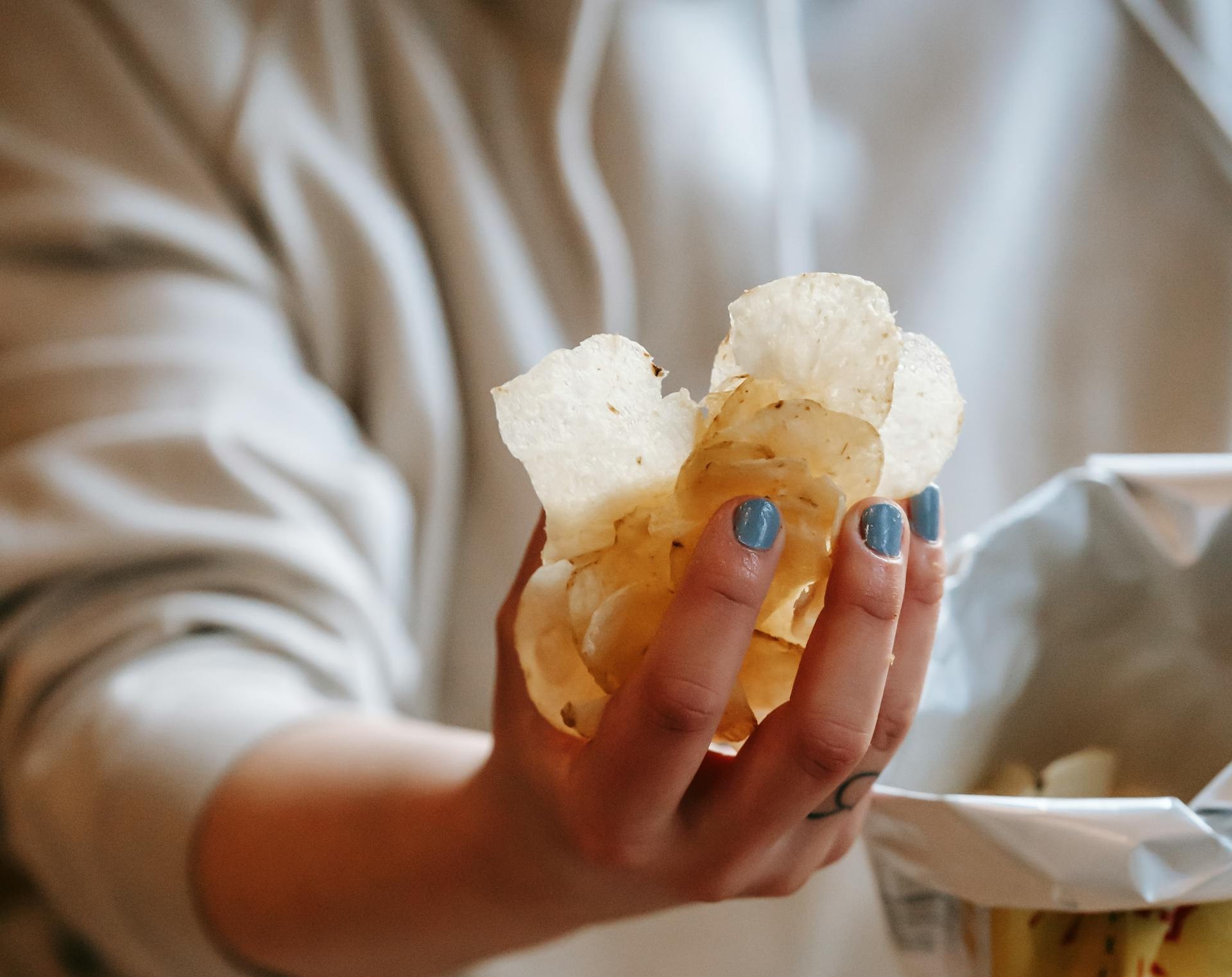 Une femme tenant une poignée de chips | Source : Pexels