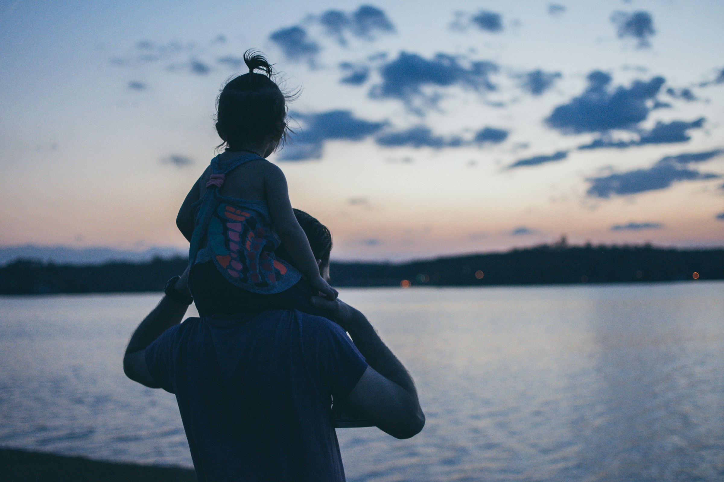 Homme portant sa fille et regardant l'eau | Source : Unsplash