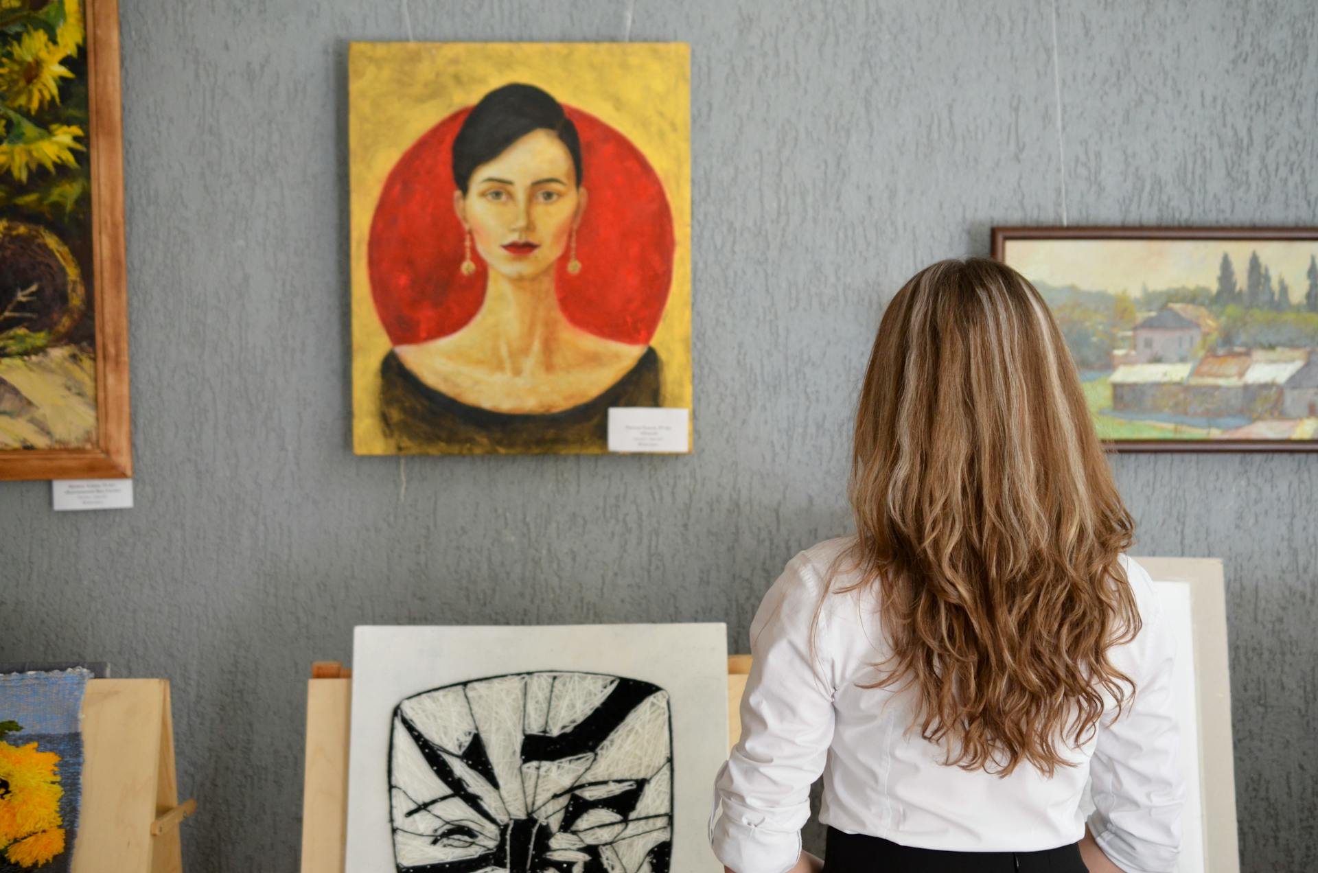 Une jeune femme regarde des peintures exposées sur un mur | Source : Pexels