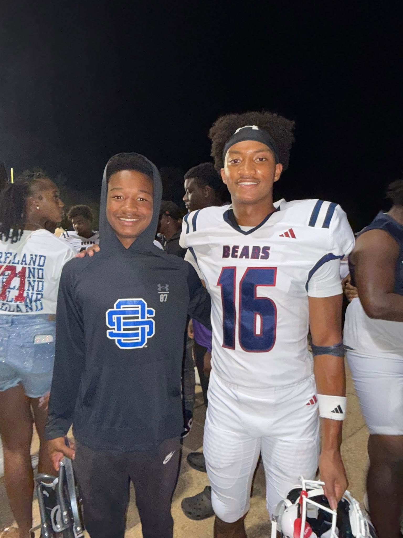 Nolan pose avec son petit frère, qui porte un maillot des Bears ; tous les deux arborent un large sourire tandis que la foule fait la fête derrière eux. | Source : Facebook/christine.wonsley