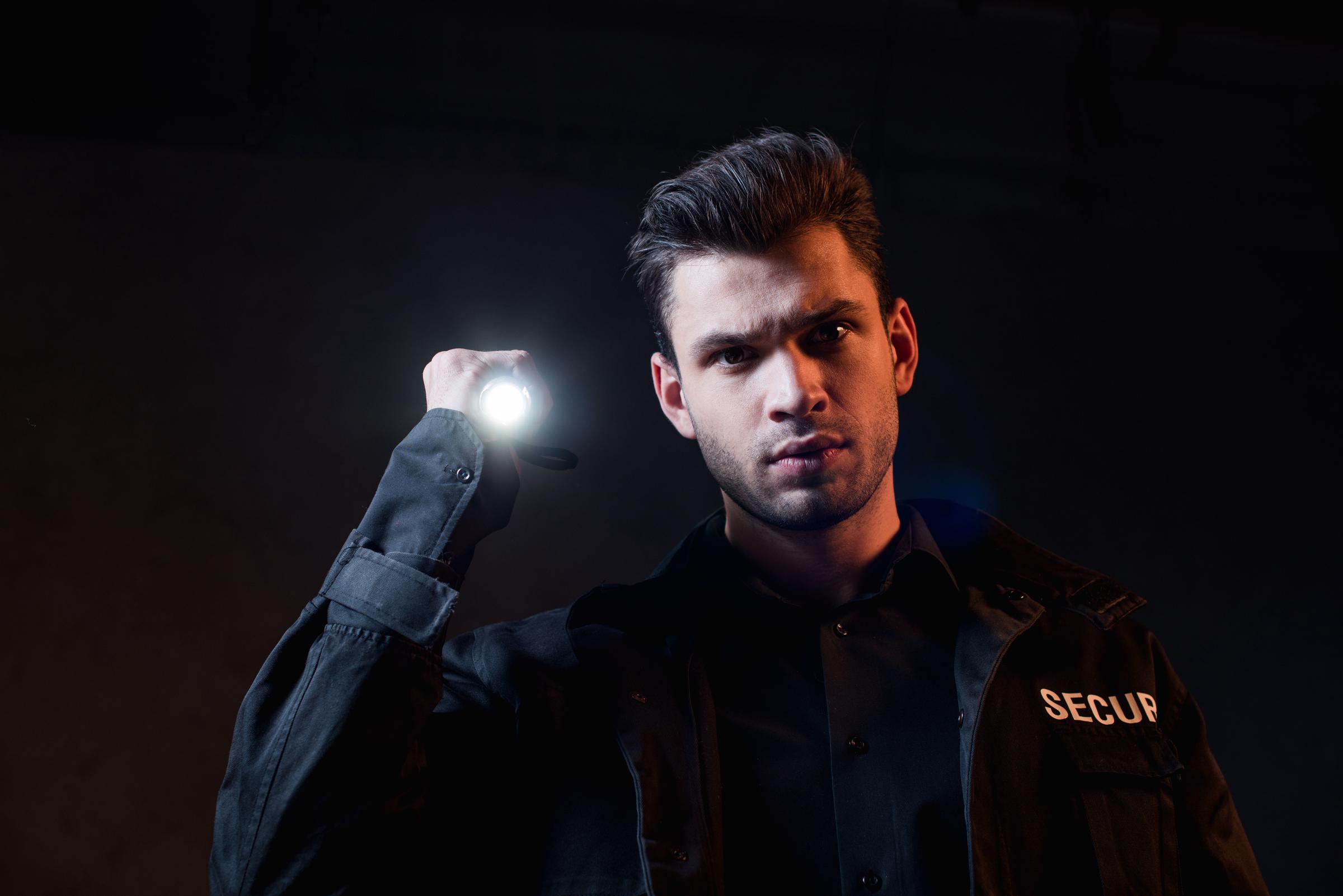 Agent de sécurité tenant une lampe de poche | Source : Shutterstock