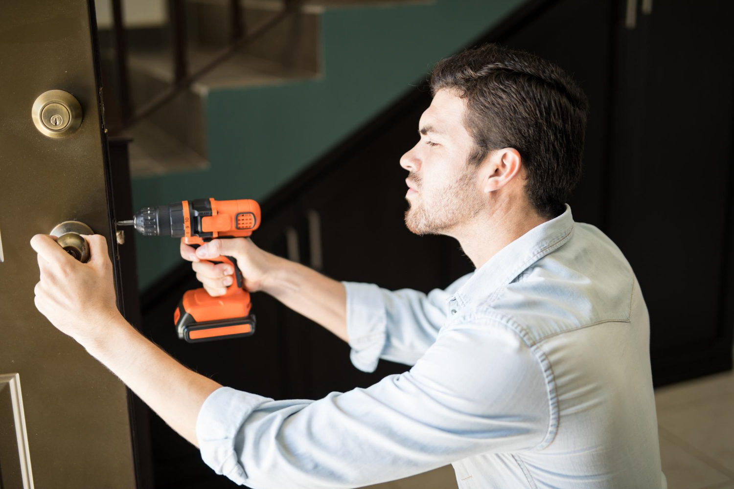 Un bricoleur utilisant une perceuse électrique pour réparer une poignée de porte | Source : Freepik