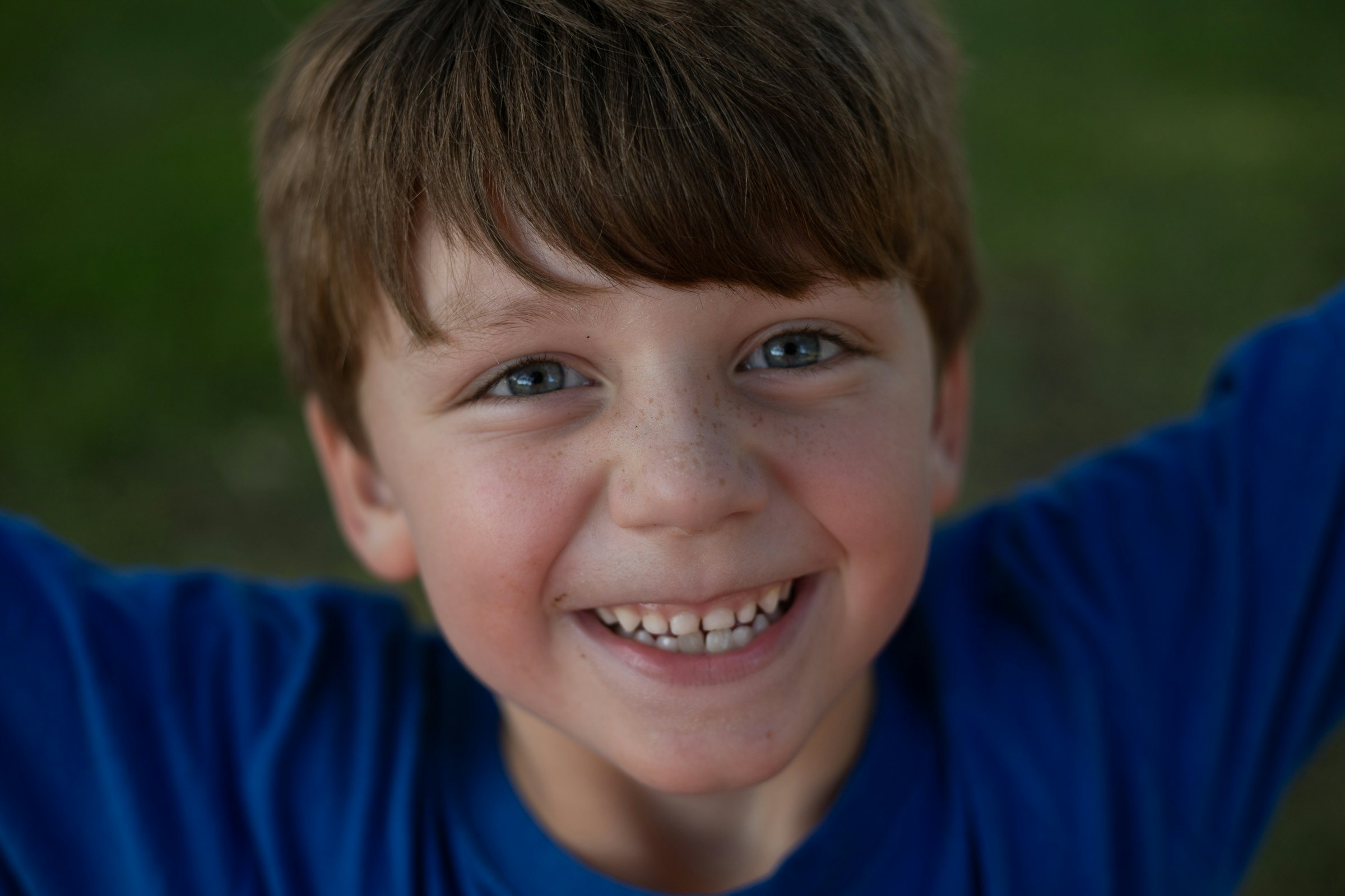 Un petit garçon souriant avec une chemise bleue | Source : Unsplash