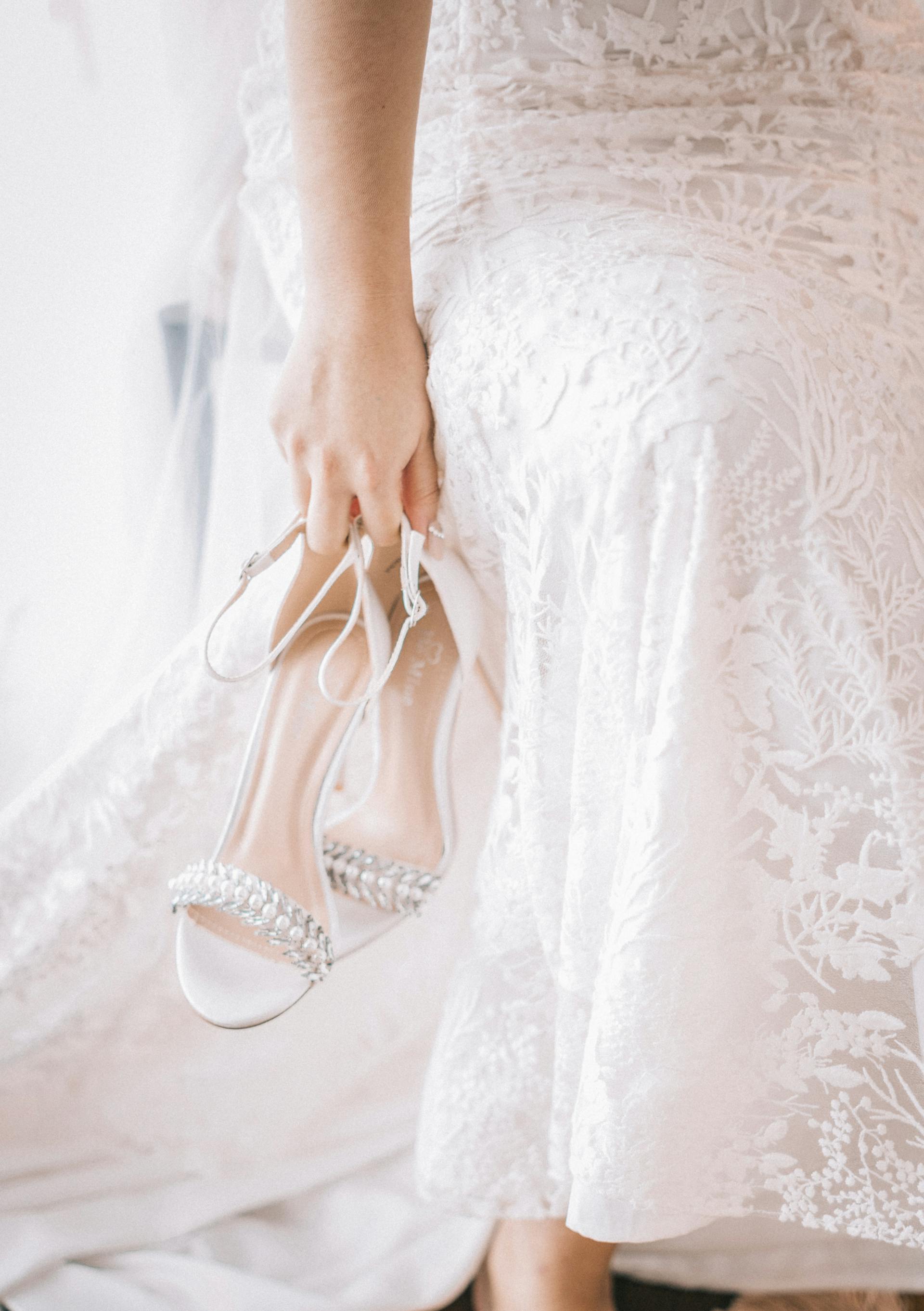 Une femme en robe blanche transportant des chaussures | Source : Pexels