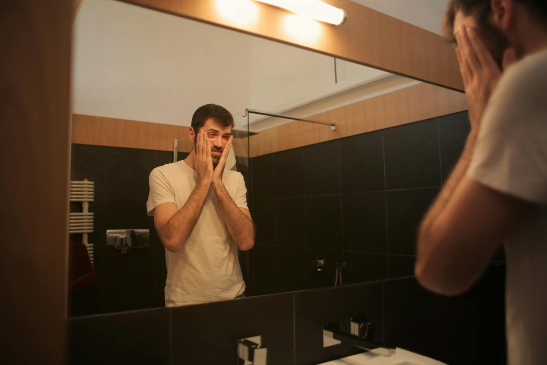 Un homme fatigué se regardant dans le miroir d'une salle de bain | Source : Pexels