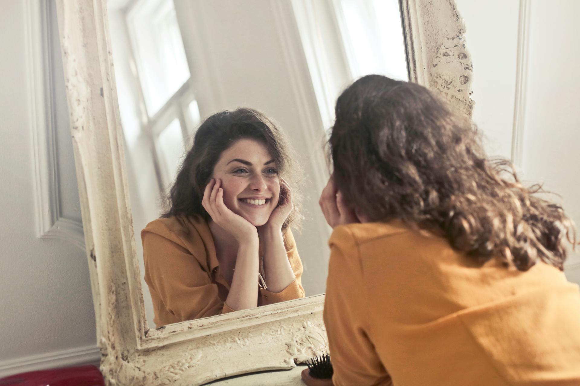 Une femme souriante qui regarde son reflet dans le miroir | Source : Pexels