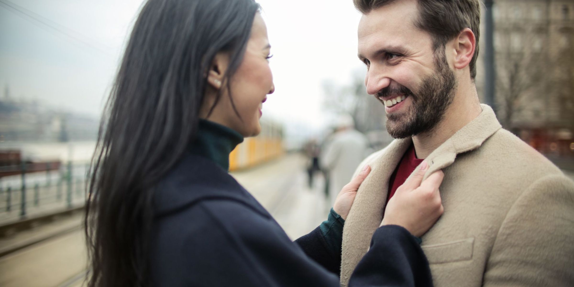 Une femme en train d'ajuster le manteau d'un homme | Source : Pexels