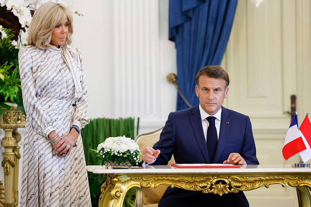 Le président français Emmanuel Macron (à droite) signe le livre d'or sous le regard de son épouse Brigitte Macron au palais Merdeka à Jakarta, le 28 mai 2025.