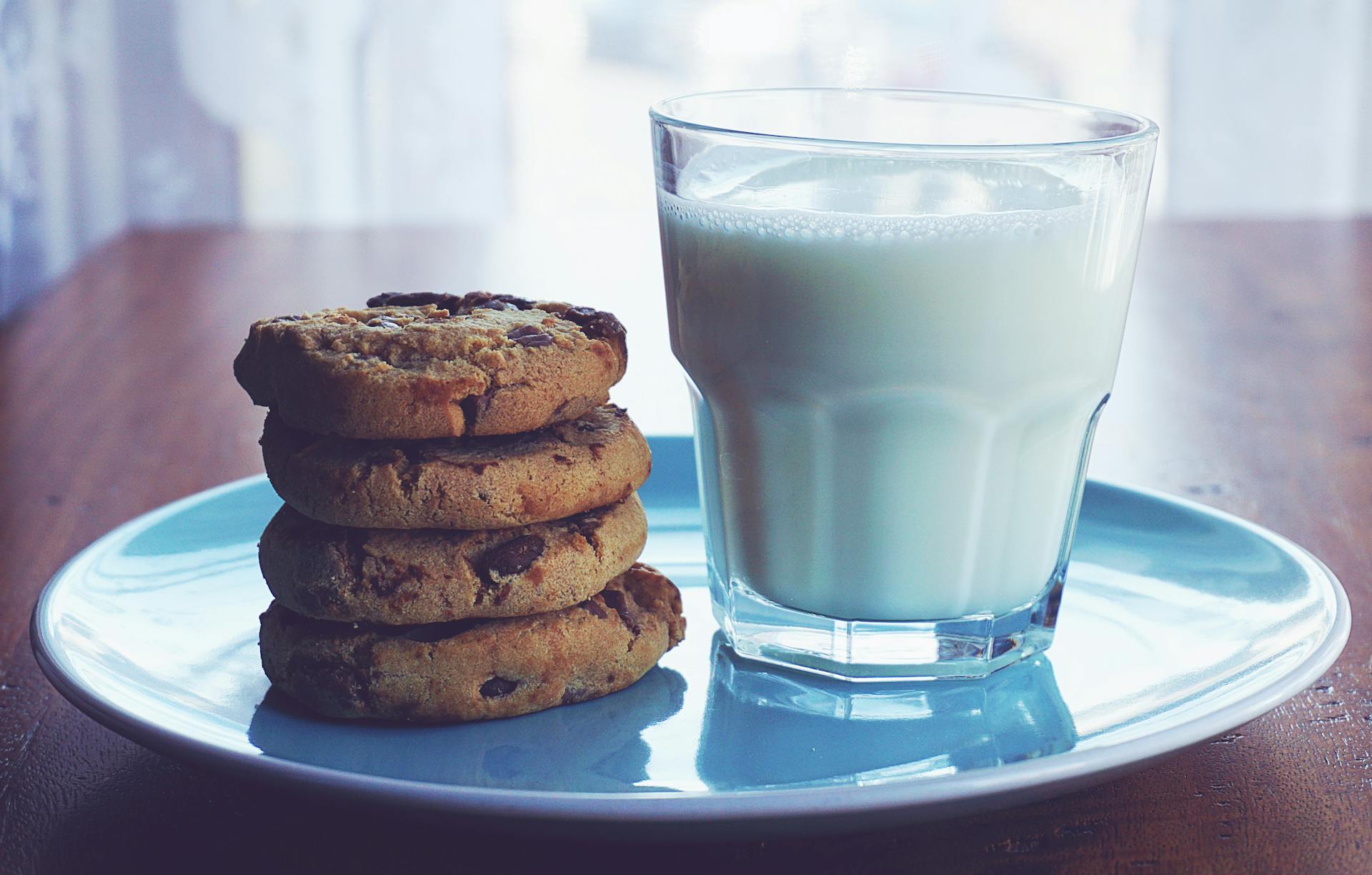 Des biscuits aux pépites de chocolat et un verre de lait | Source : Midjourney