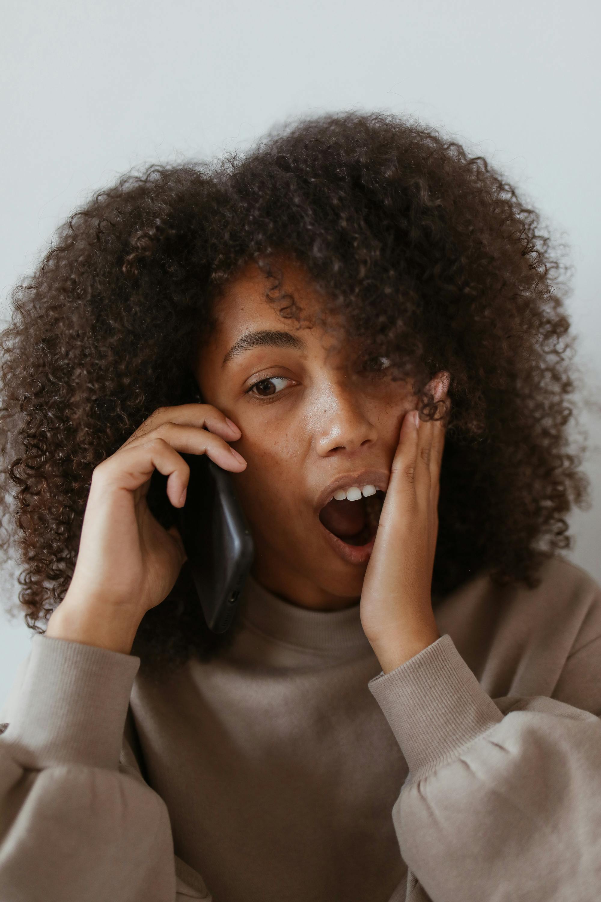 Une femme réagissant sous le choc alors qu'elle est au téléphone | Source : Pexels
