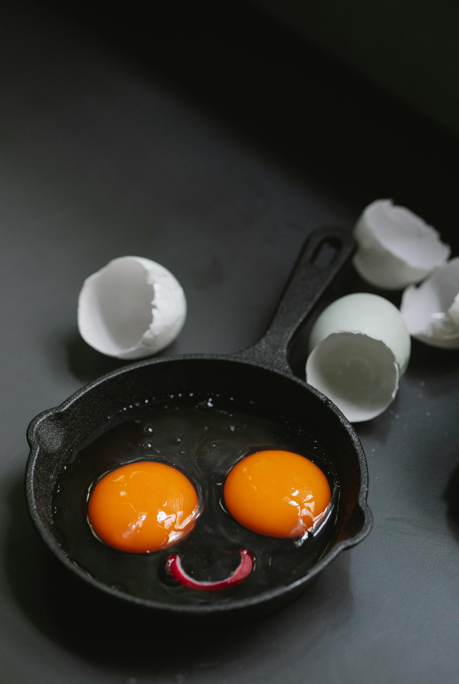 Une poêle à frire avec des jaunes d'œufs formant un drôle de visage | Source : Pexels