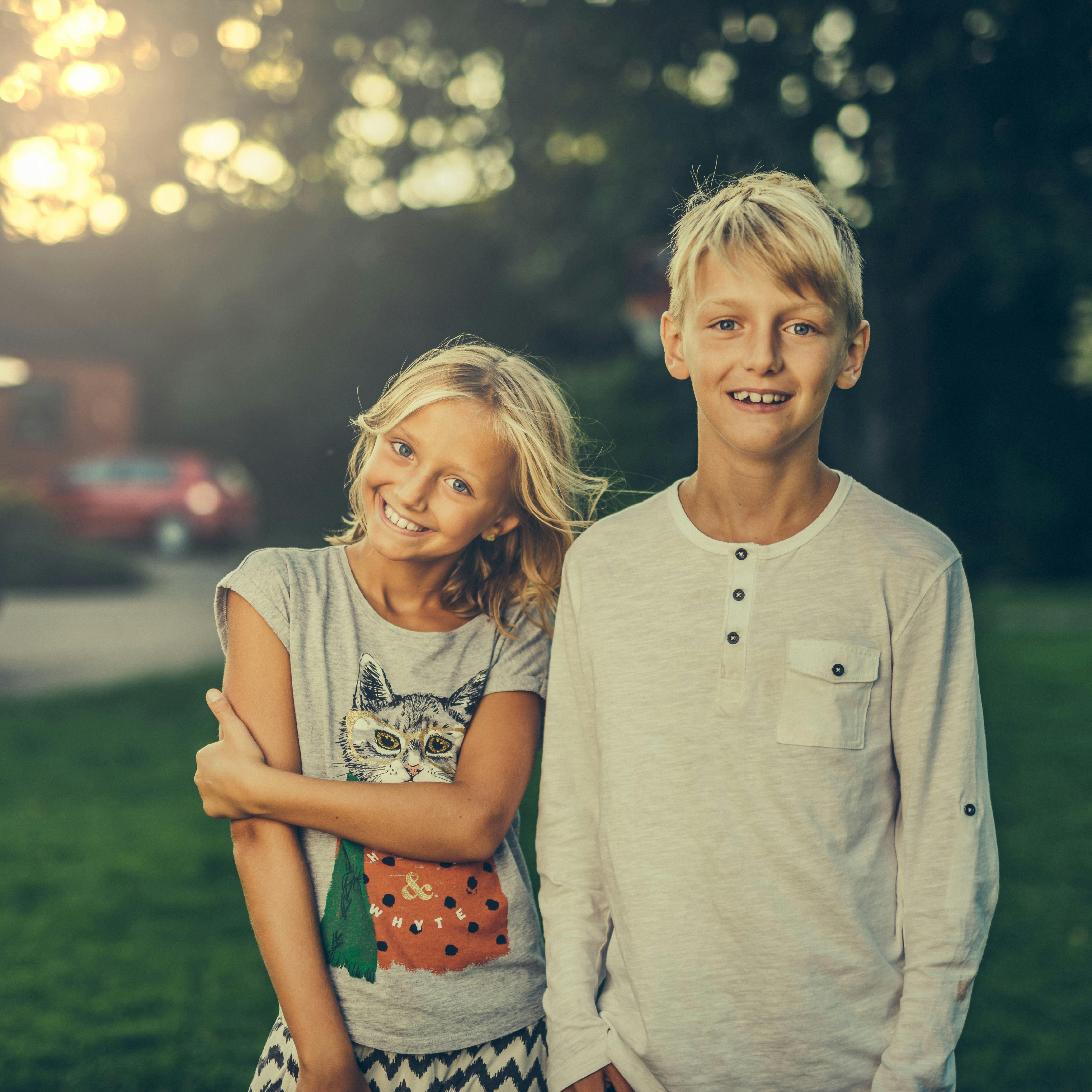 Un frère et une sœur souriant en se tenant côte à côte | Source : Pexels