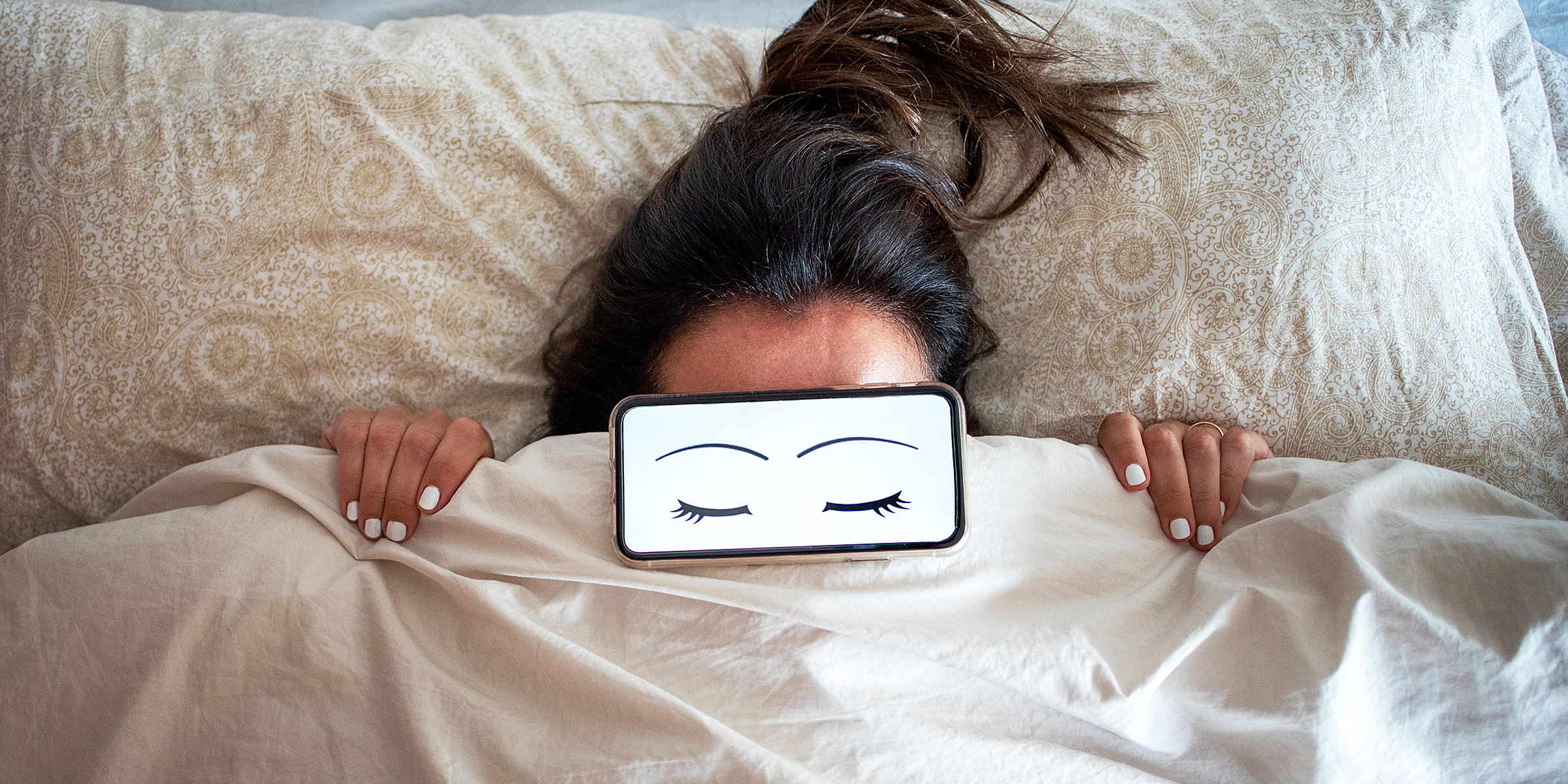 Une femme au lit avec des yeux de dessin animé sur son visage | Source : Getty Images