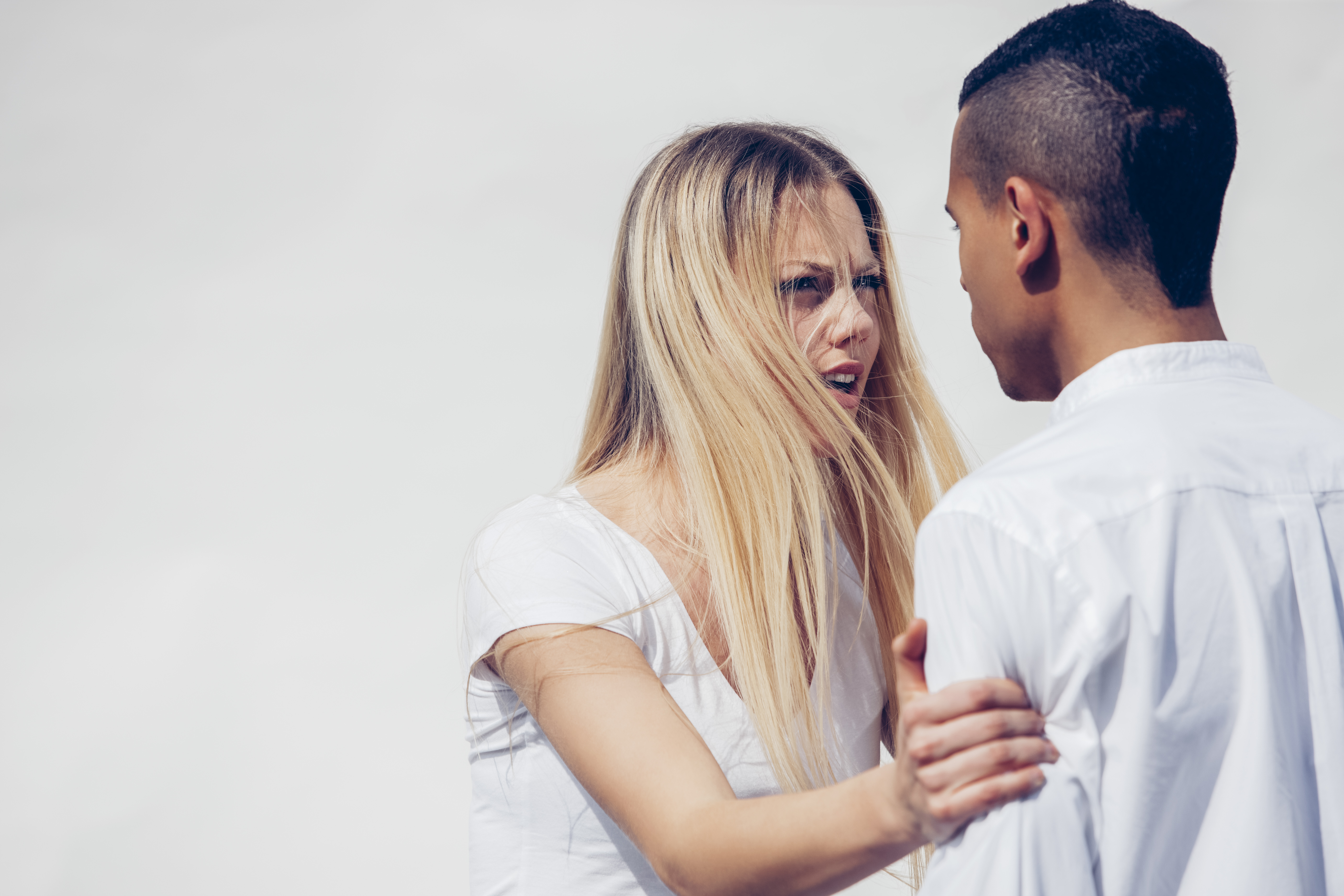 Portrait d'une jeune femme en colère face à son petit ami devant un fond blanc | Source : Getty Images