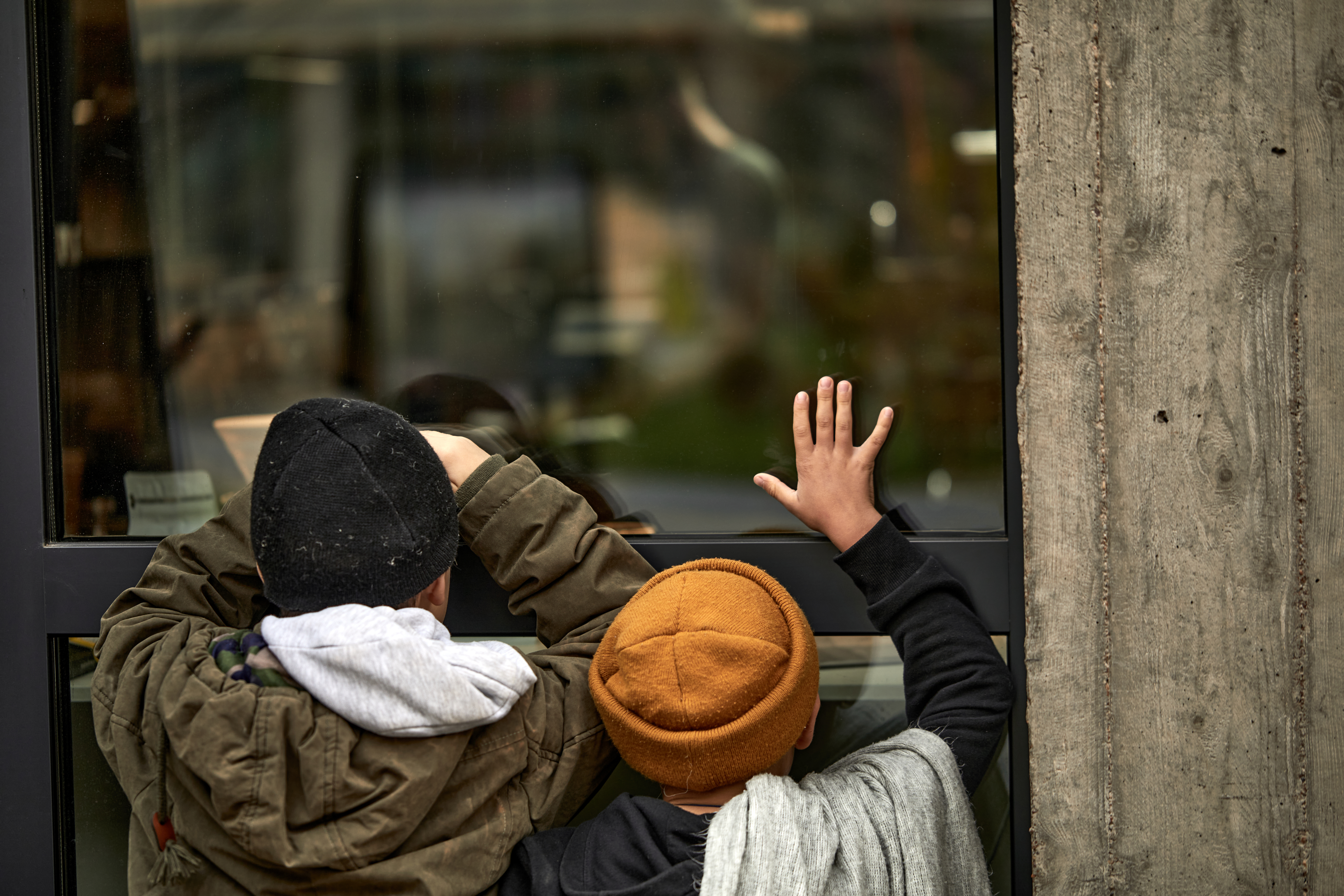 Dos niños pobres sin hogar apoyados en la ventana de un edificio | Fuente: Shutterstock.com