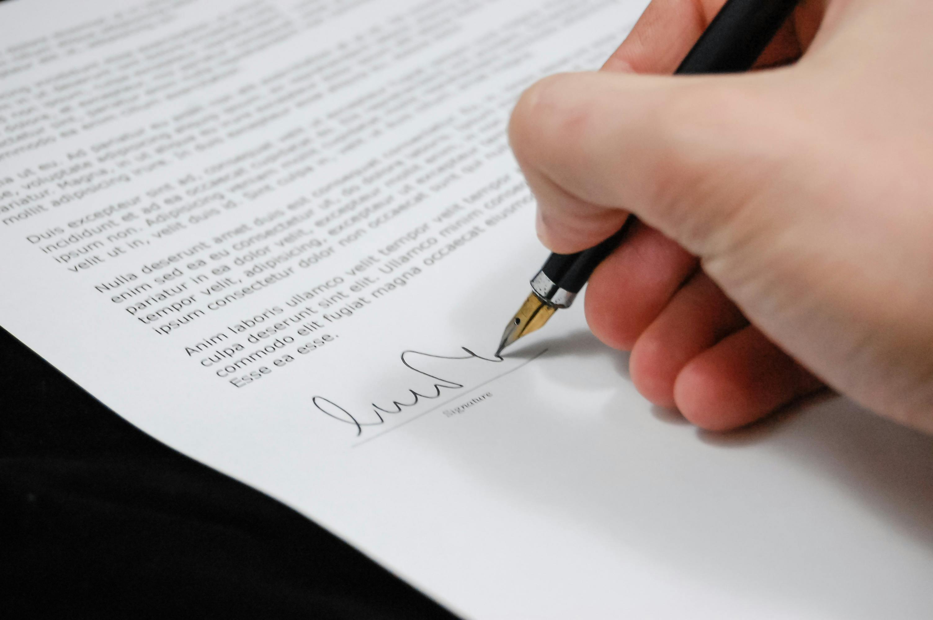 Un homme signant des documents juridiques | Source : Pexels