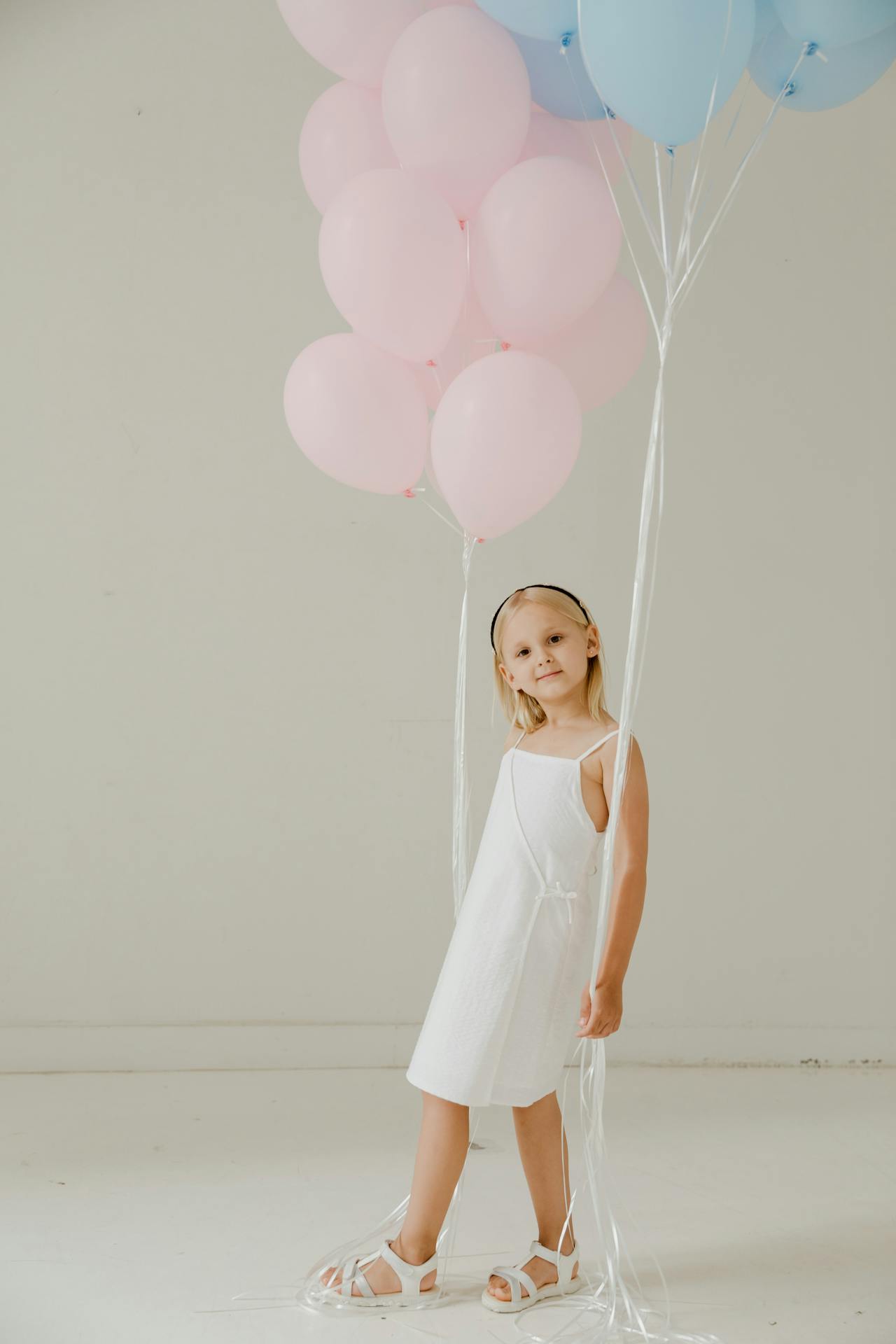 Une petite fille excitée tenant des ballons roses et bleus | Source : Pexels