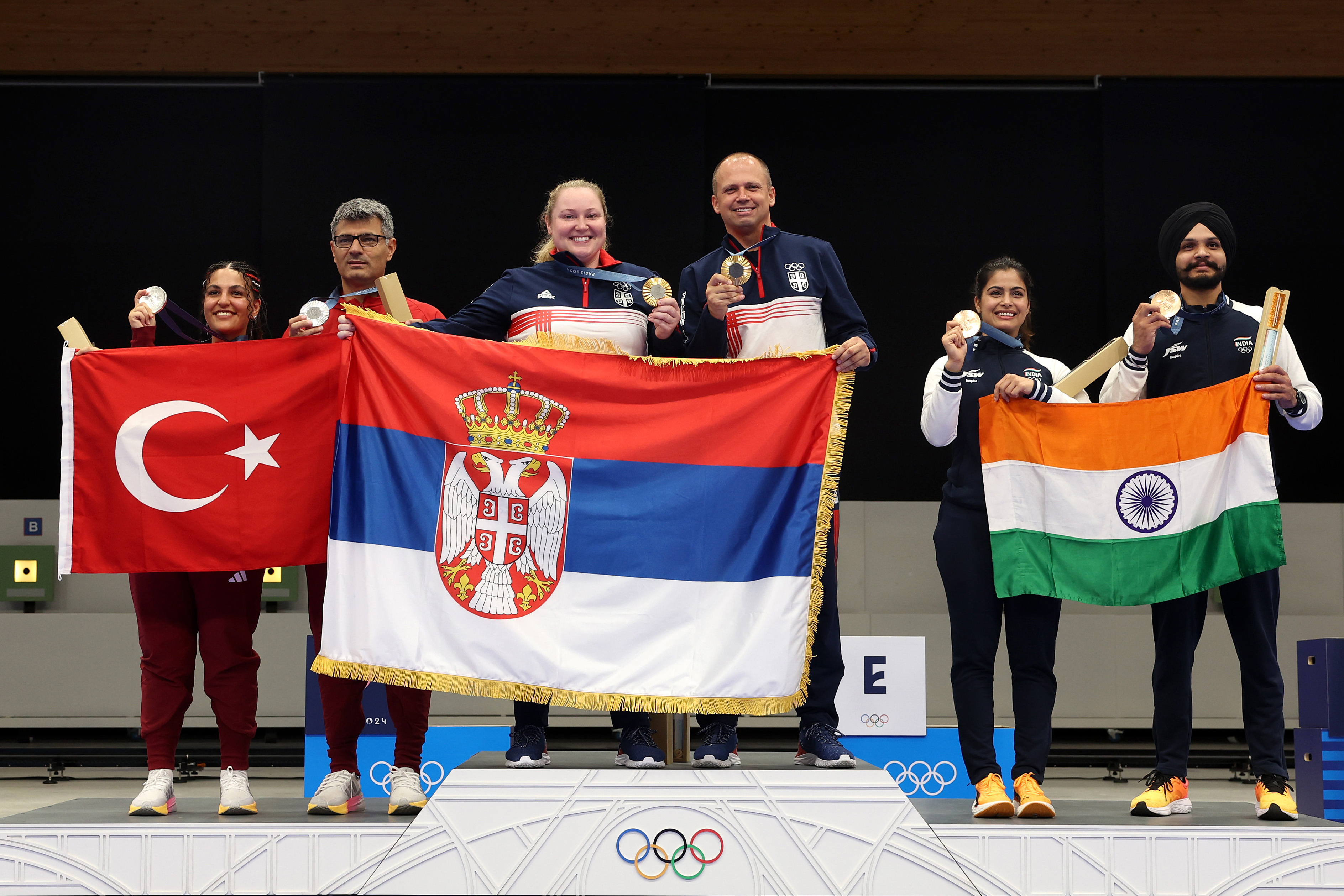 Sevval Ilayda Tarhan et Yusuf Dikeç, Zorana Arunovic et Damir Mikec, et Manu Bhaker et Sarabjot Singh posent sur le podium lors de la cérémonie de remise des médailles de l'équipe mixte de tir au pistolet à air comprimé 10 m aux Jeux olympiques de Paris, le 30 juillet 2024, à Châteauroux, en France | Source : Getty Images