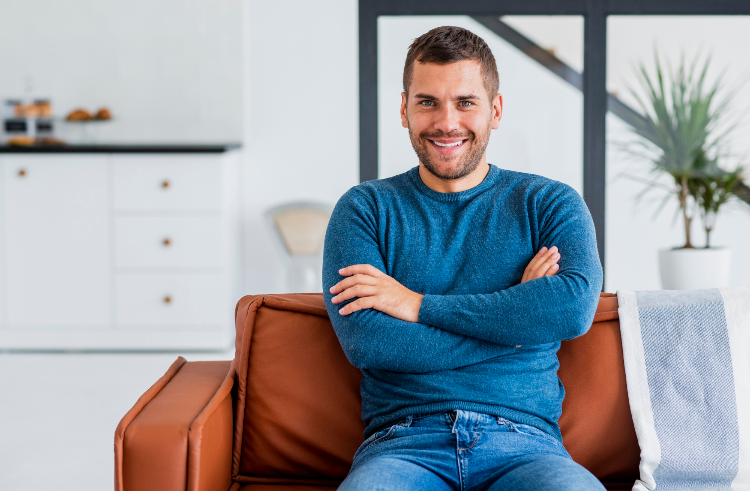 Un homme souriant assis sur le canapé | Source : Freepik